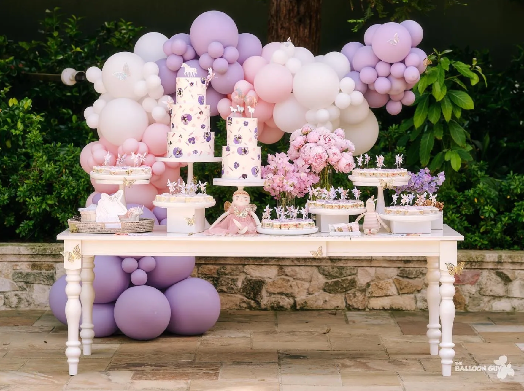 A table decorated with balloons and cakes for a birthday party.