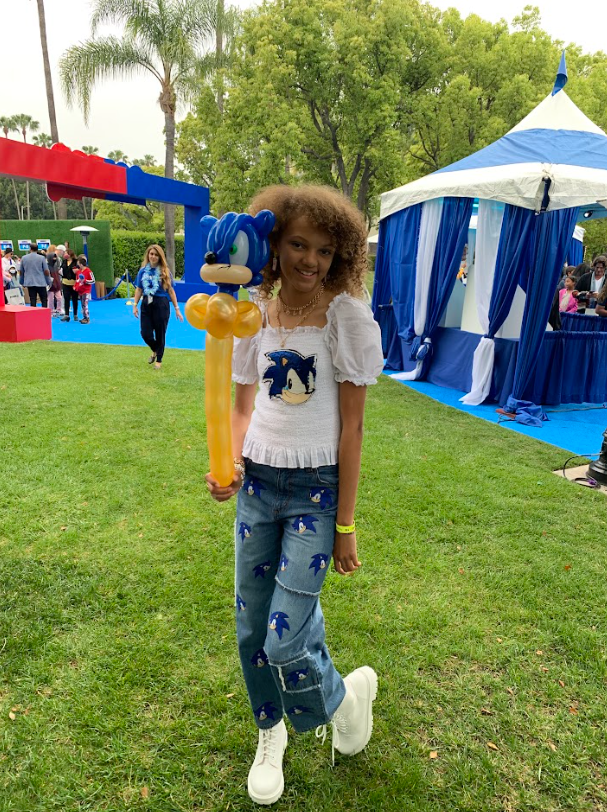 A little girl is holding a balloon of sonic the hedgehog.