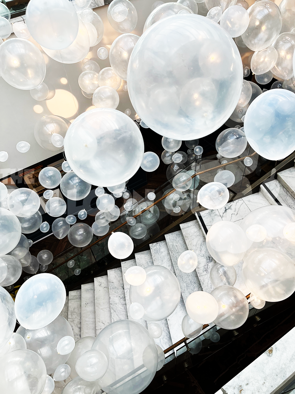 A bunch of white balloons are hanging from the ceiling