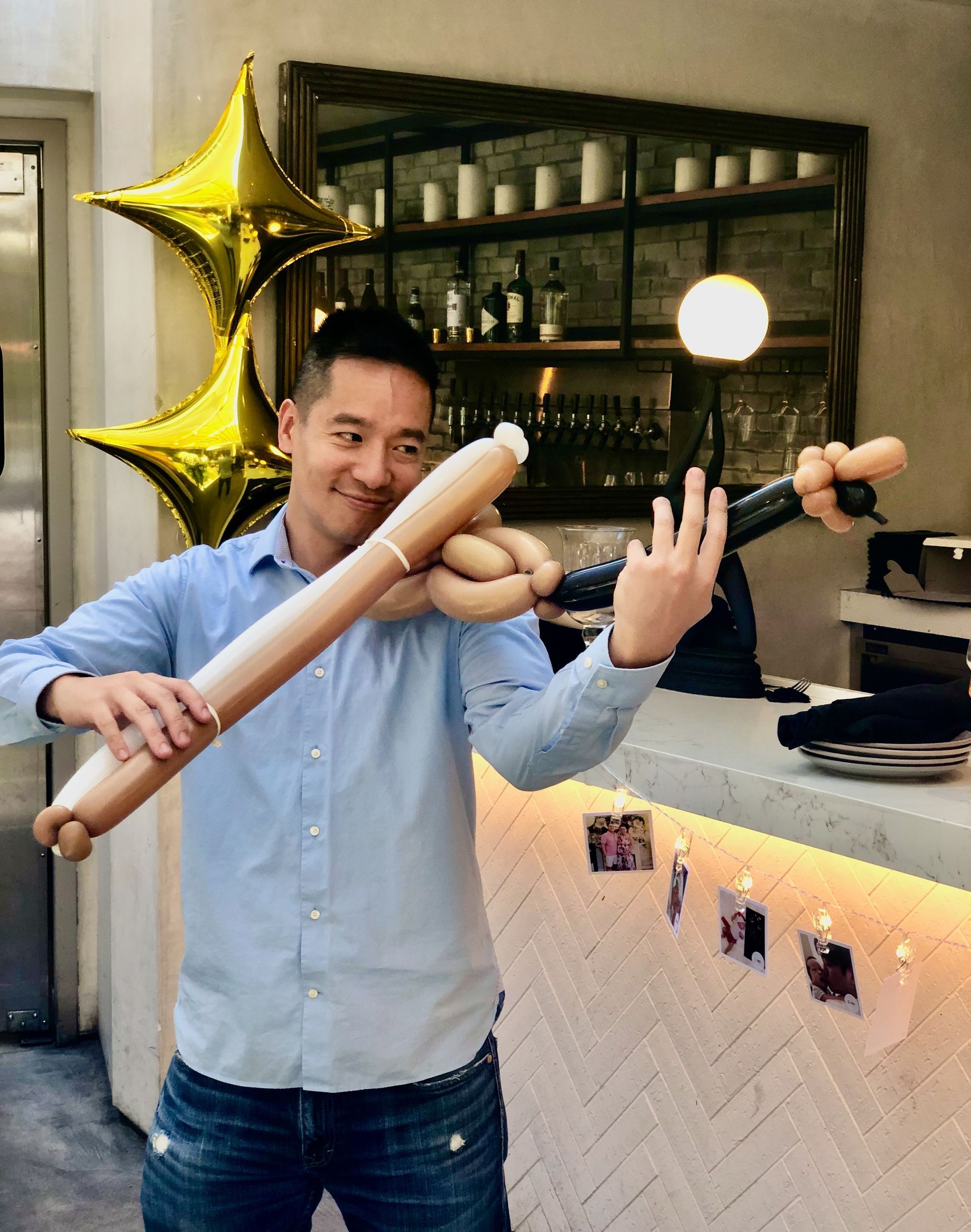 A man is holding a baseball bat made out of balloons.