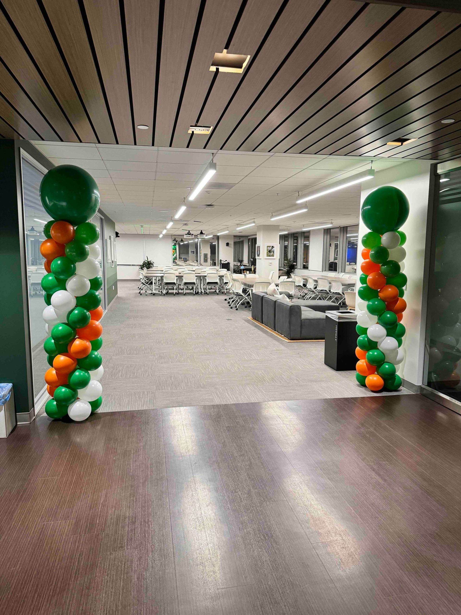 A hallway with two columns of balloons in green , white and orange.  Balloon Towers for non-profits and charity events.