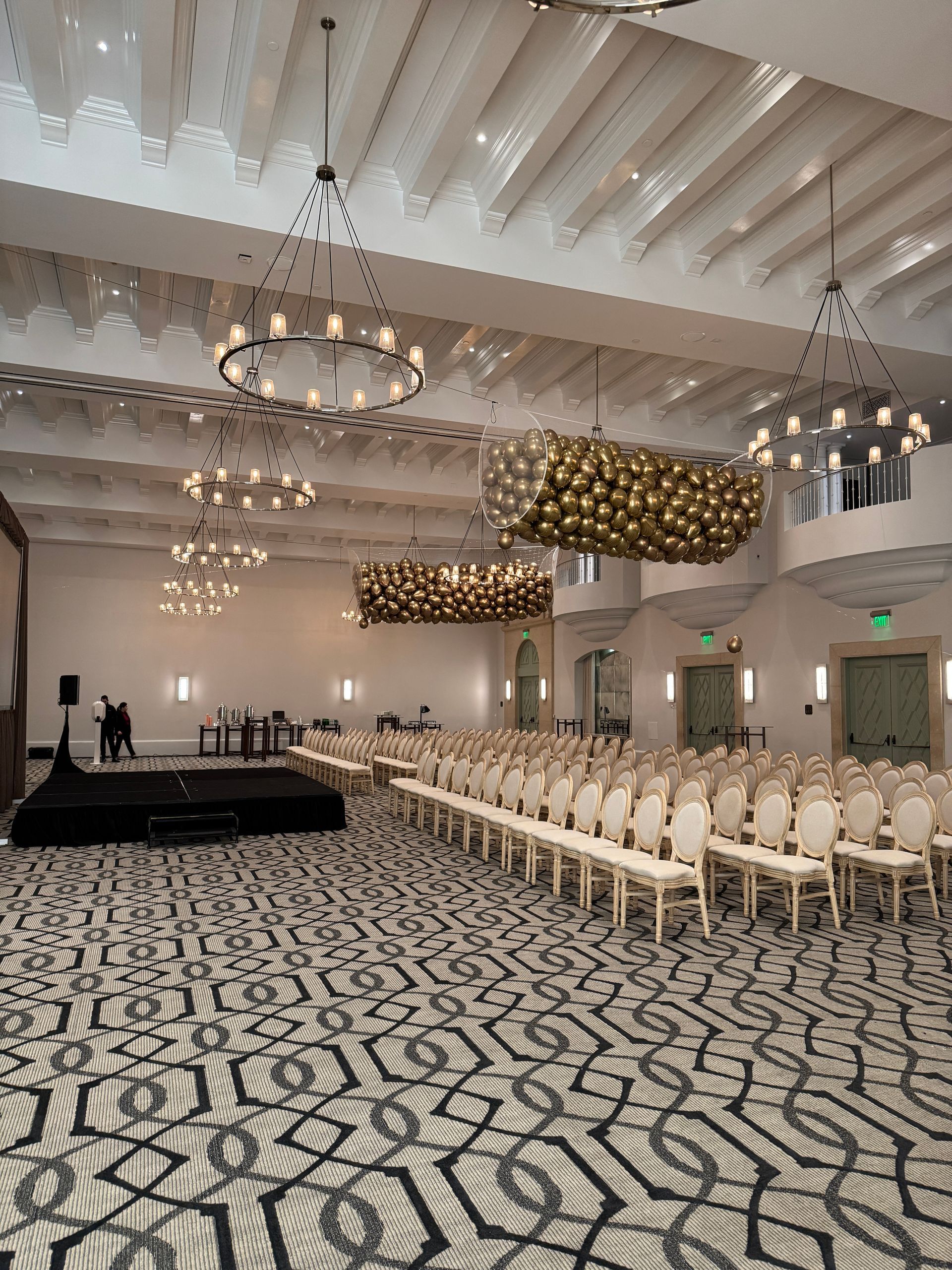 A large room with rows of chairs and chandeliers hanging from the ceiling