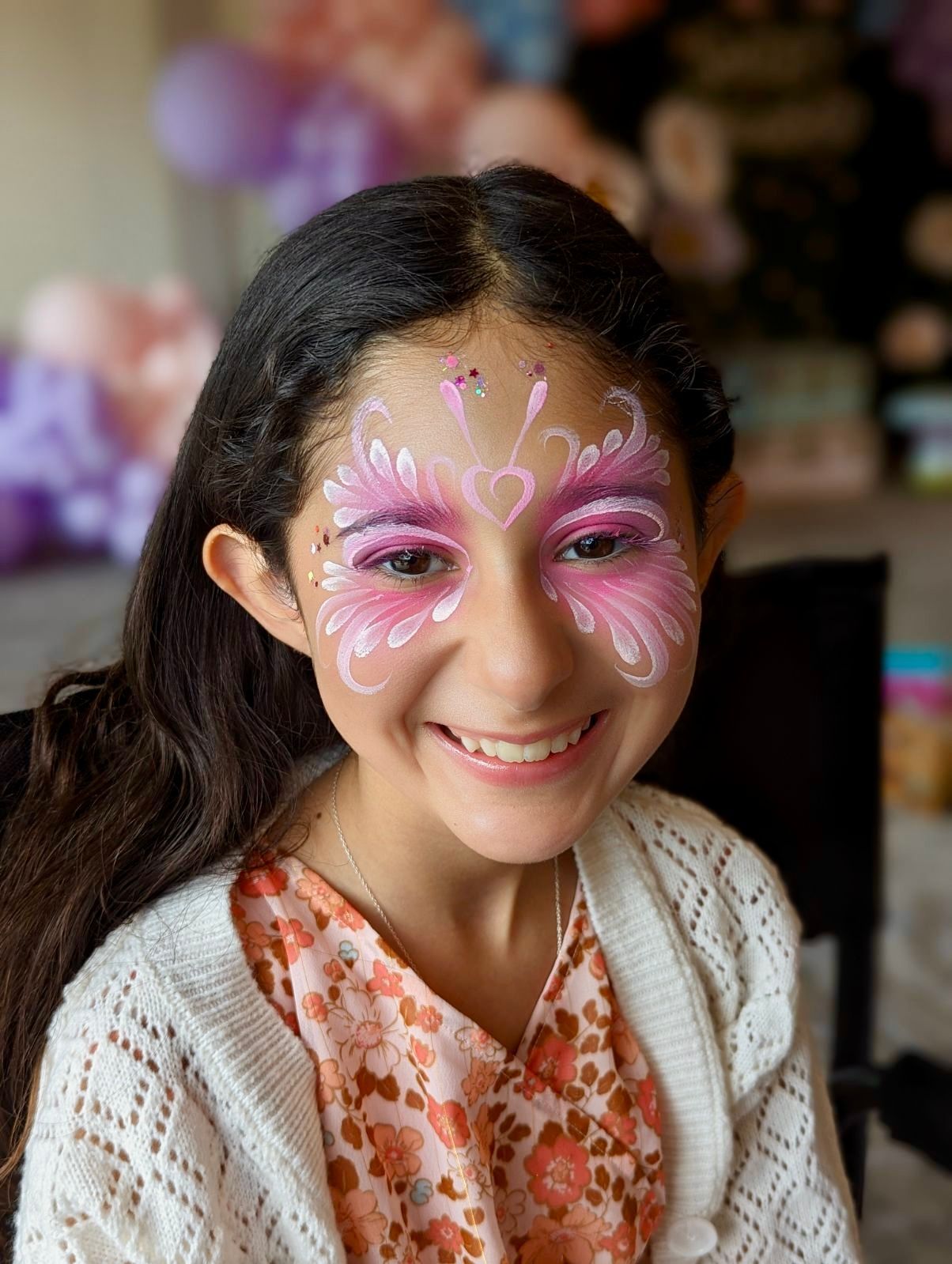 A young girl with a pink butterfly painted on her face.
