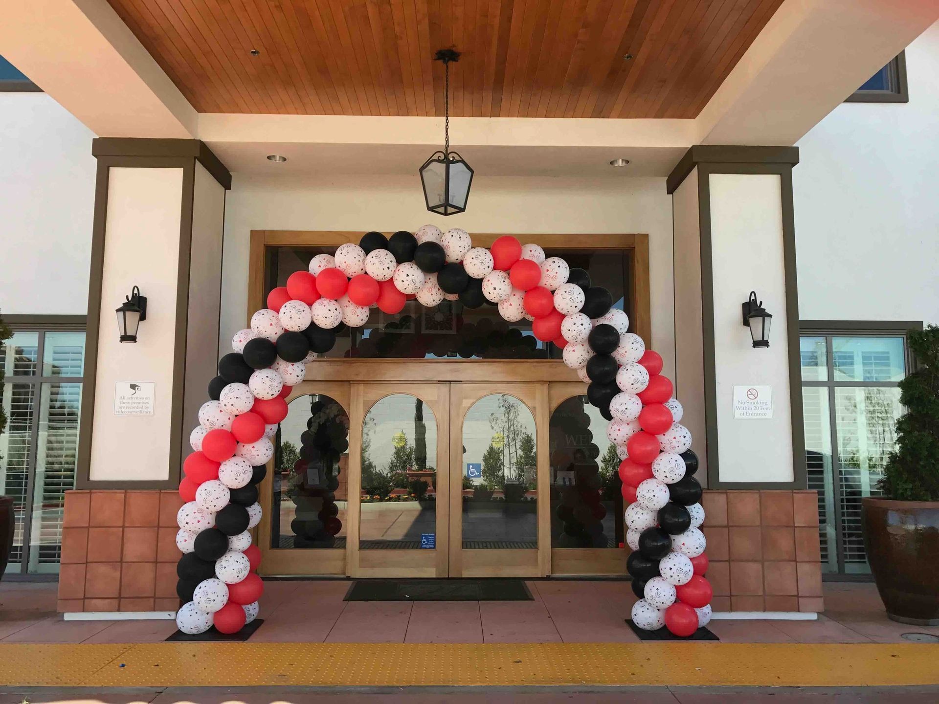 A red white and black balloon arch in front of a building