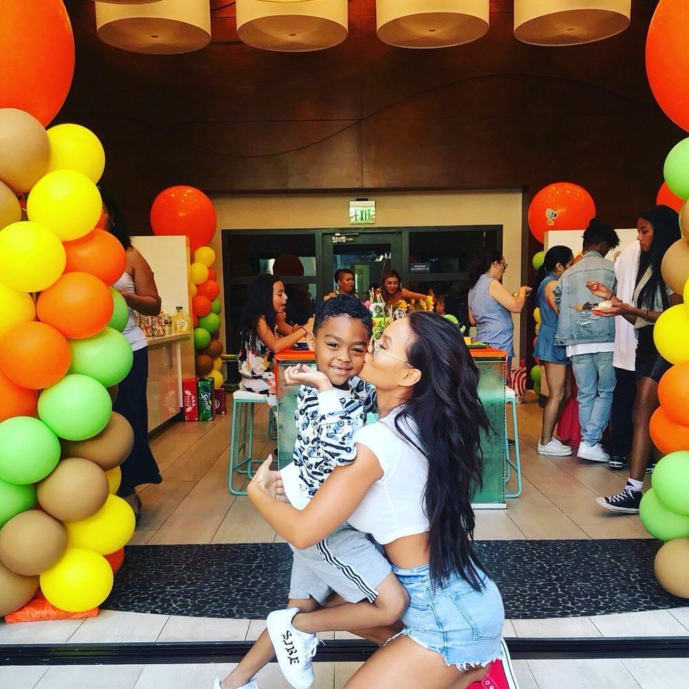 A woman is holding a little boy in her arms in front of balloons