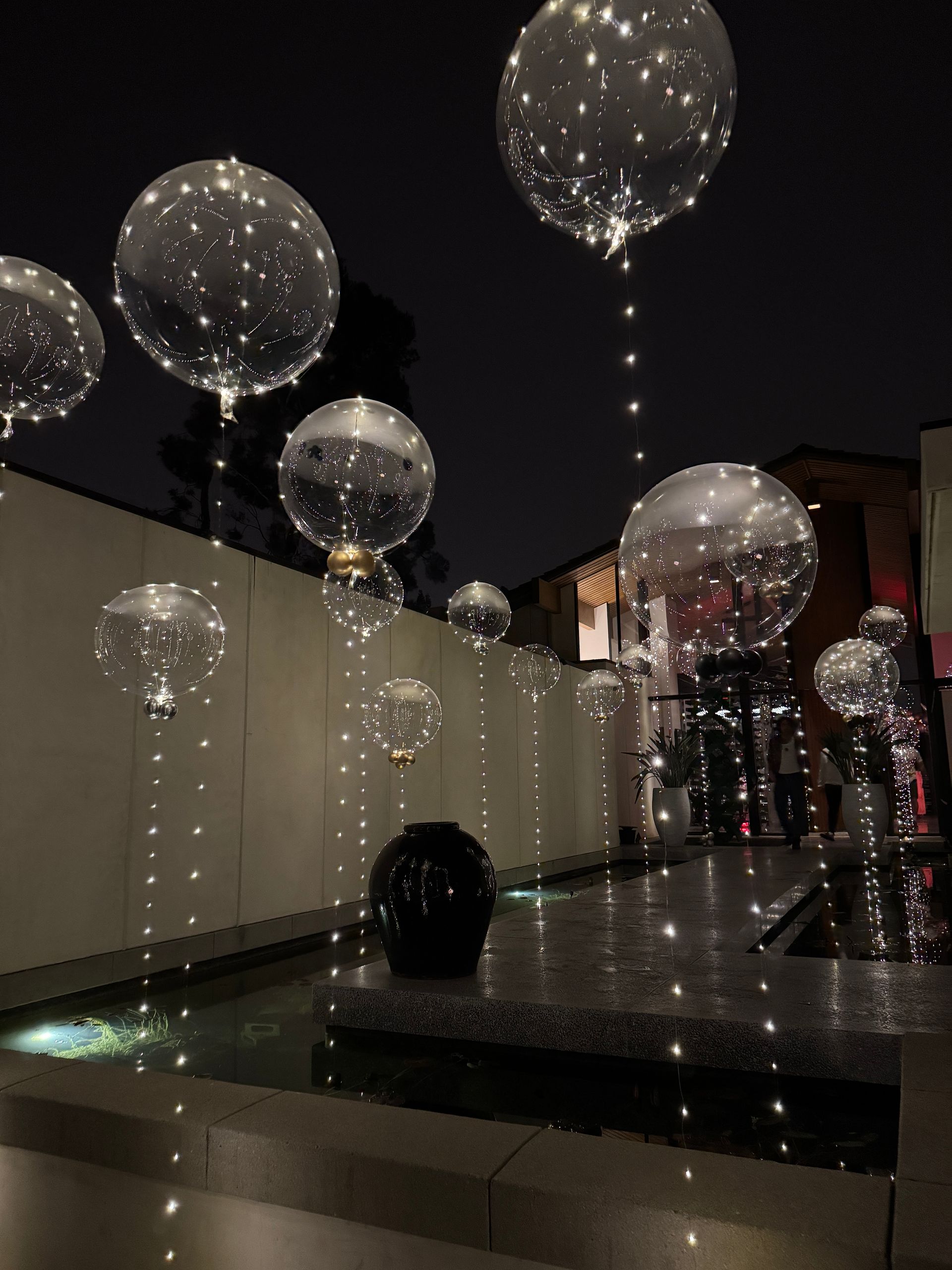 A bunch of clear balloons with lights hanging from them