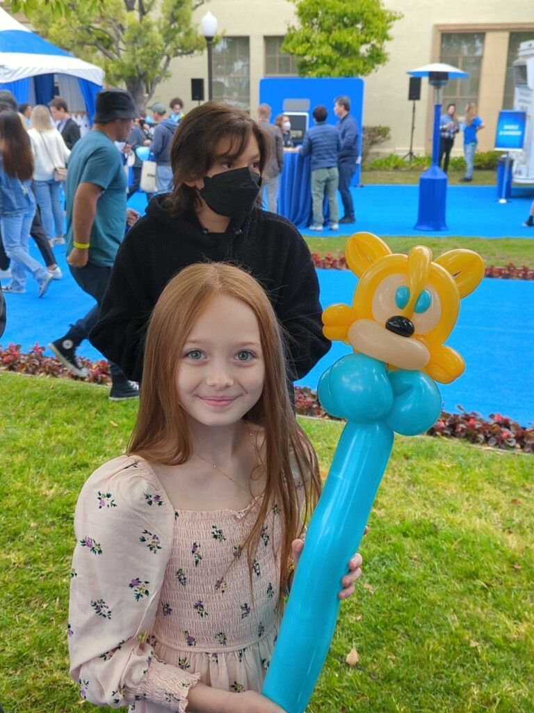 A little girl is holding a balloon in the shape of a character from the sonic 2 movie