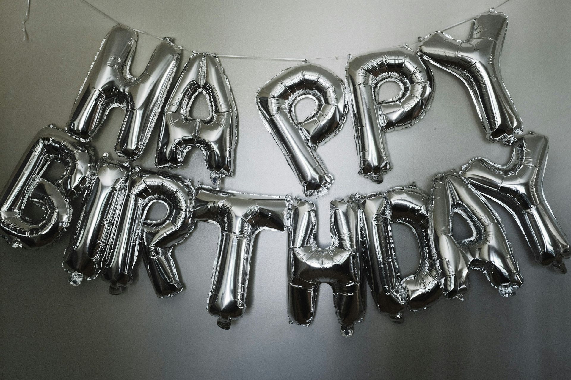 A bunch of silver balloons that say happy birthday