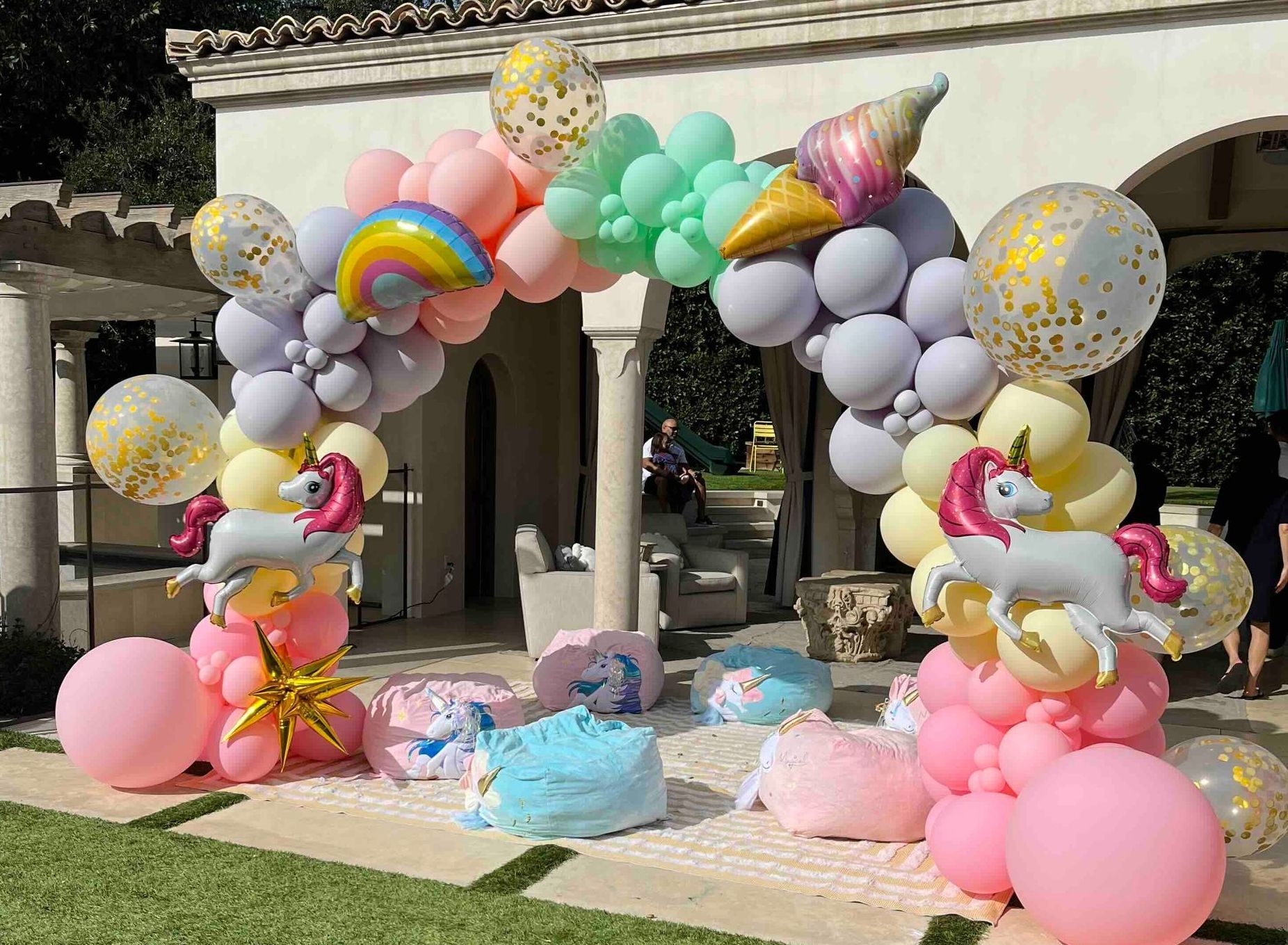 A bunch of balloons with unicorns on them are sitting in front of a building.