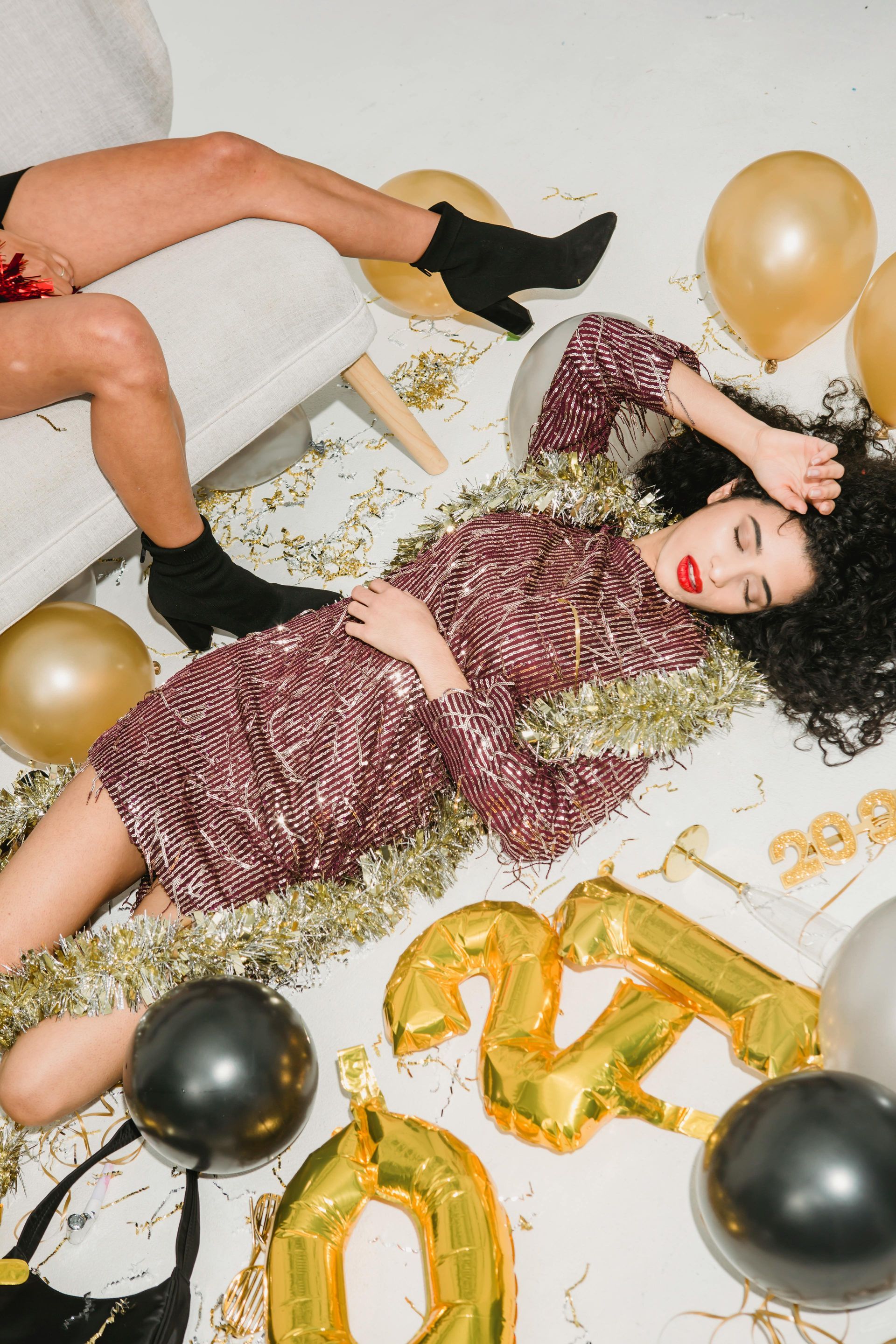 Two women are laying on the floor with balloons and confetti.