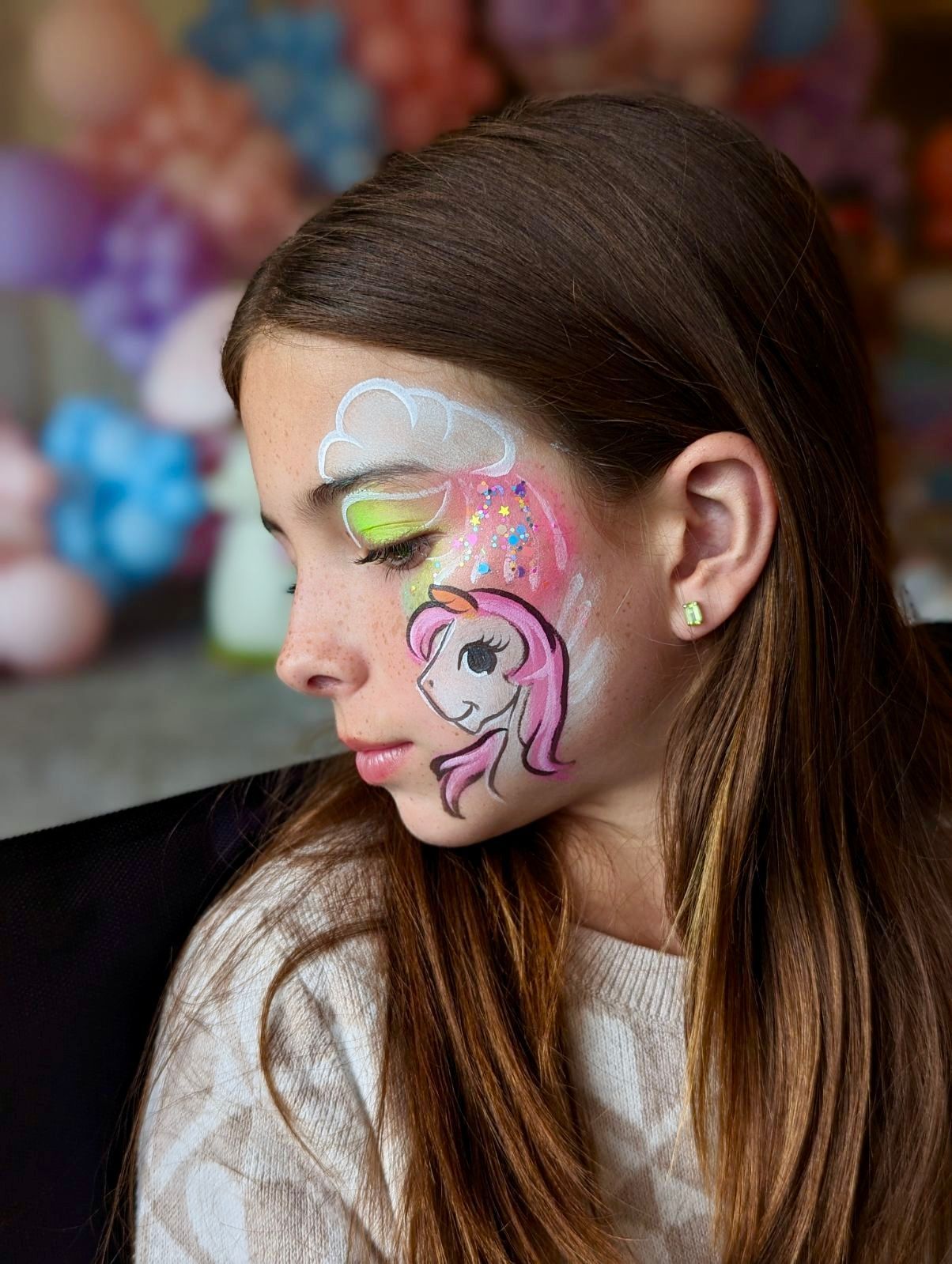 A young girl with a unicorn painted on her face.