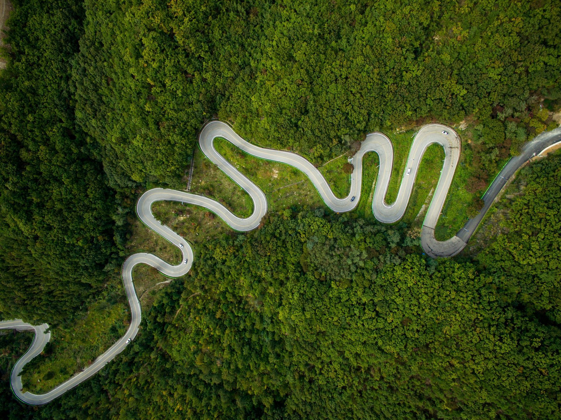 An aerial view of a winding road through a forest.