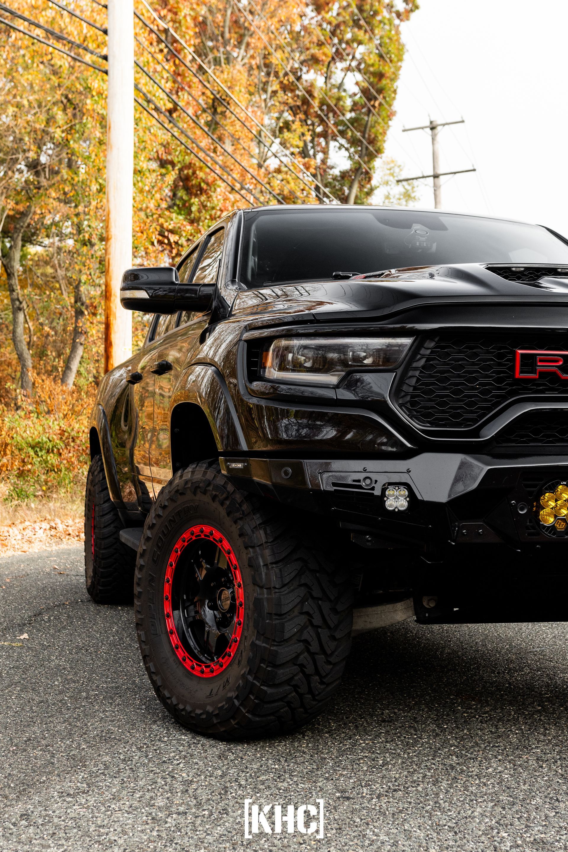 Black Ram TRX truck with red accents parked on a road with fall foliage.