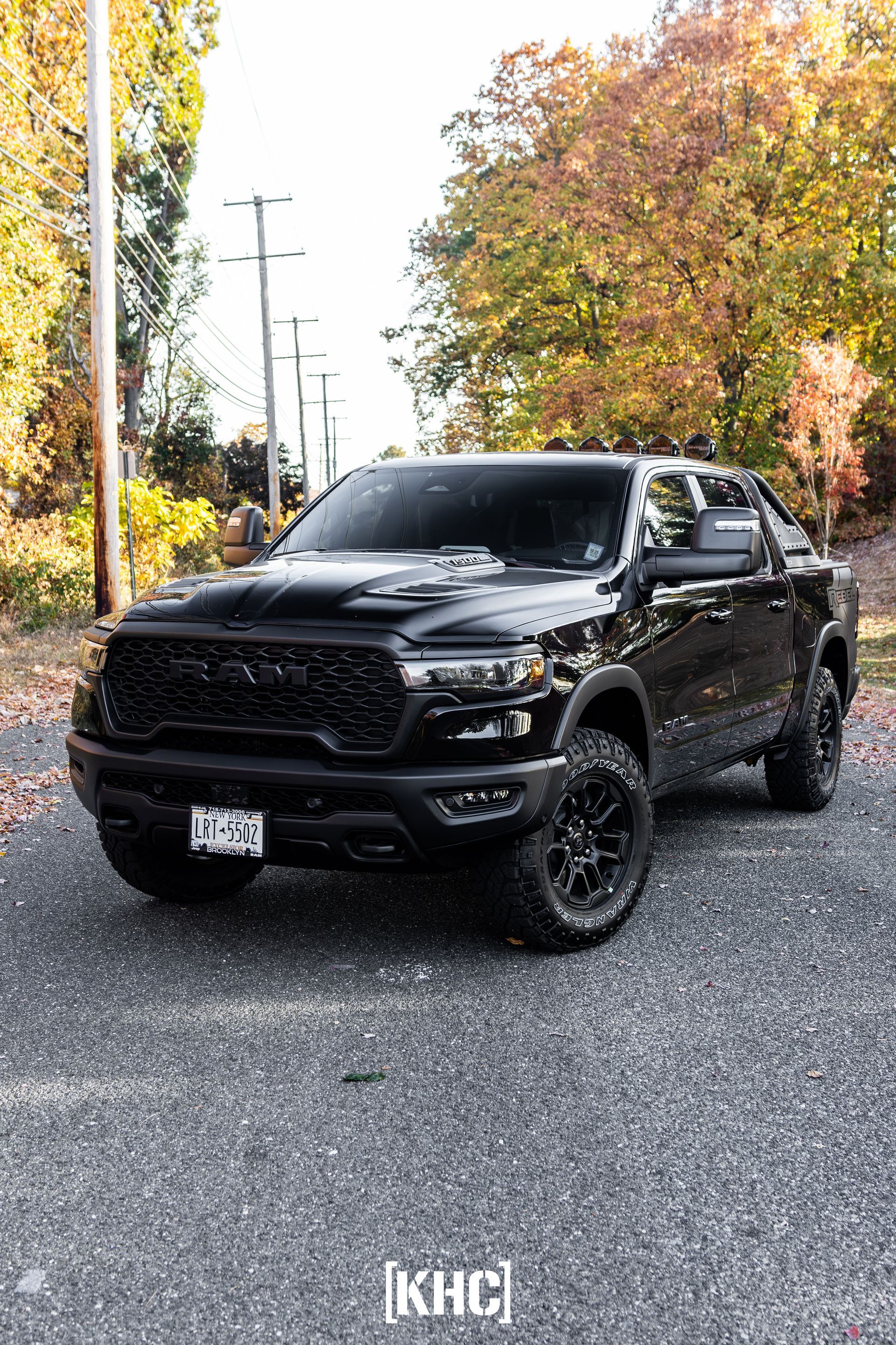 Black Ram truck parked on a gravel road, autumn leaves in background.