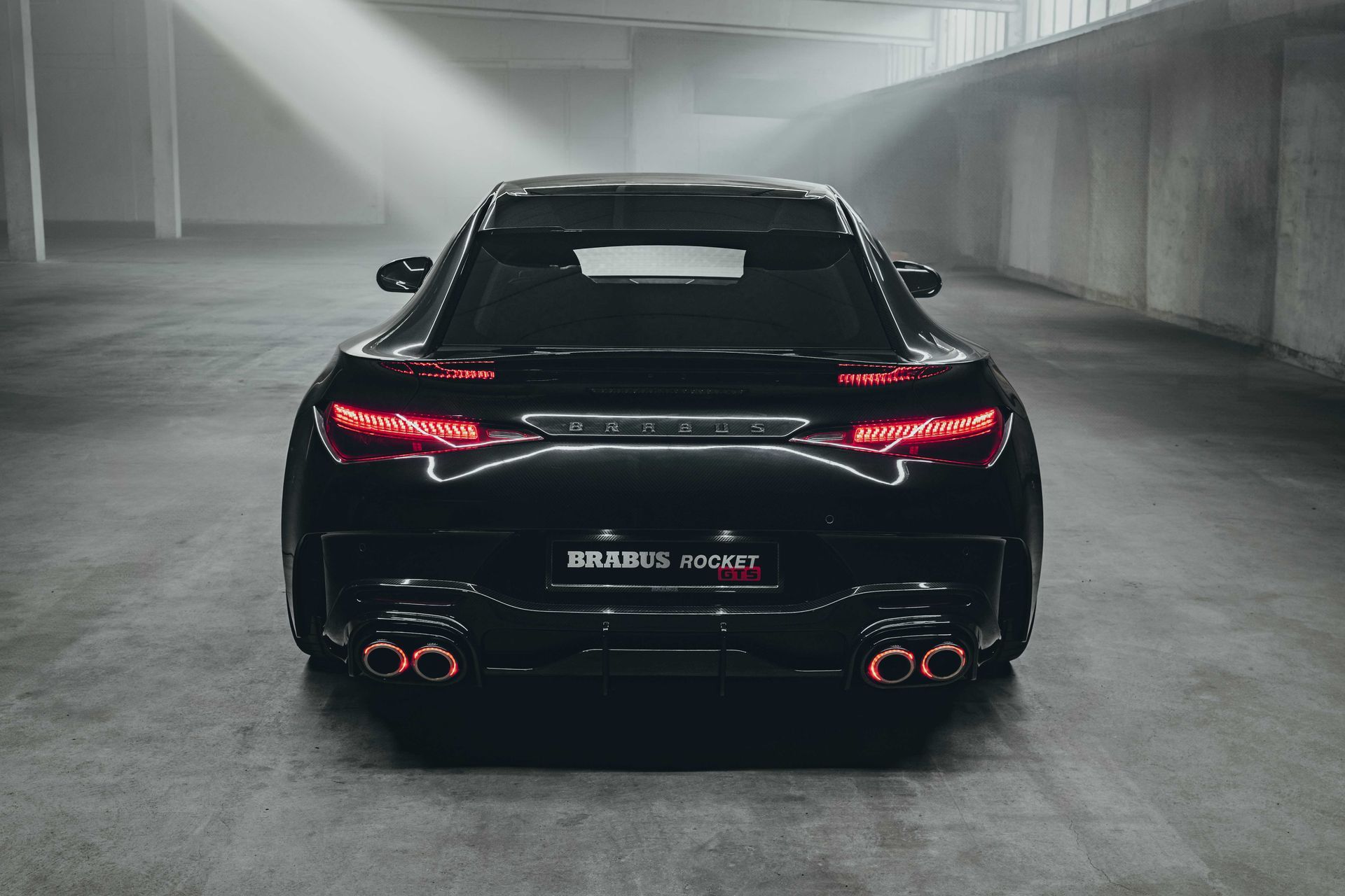 Rear view of a black high performance sports car with illuminated LED taillights in a modern garage.