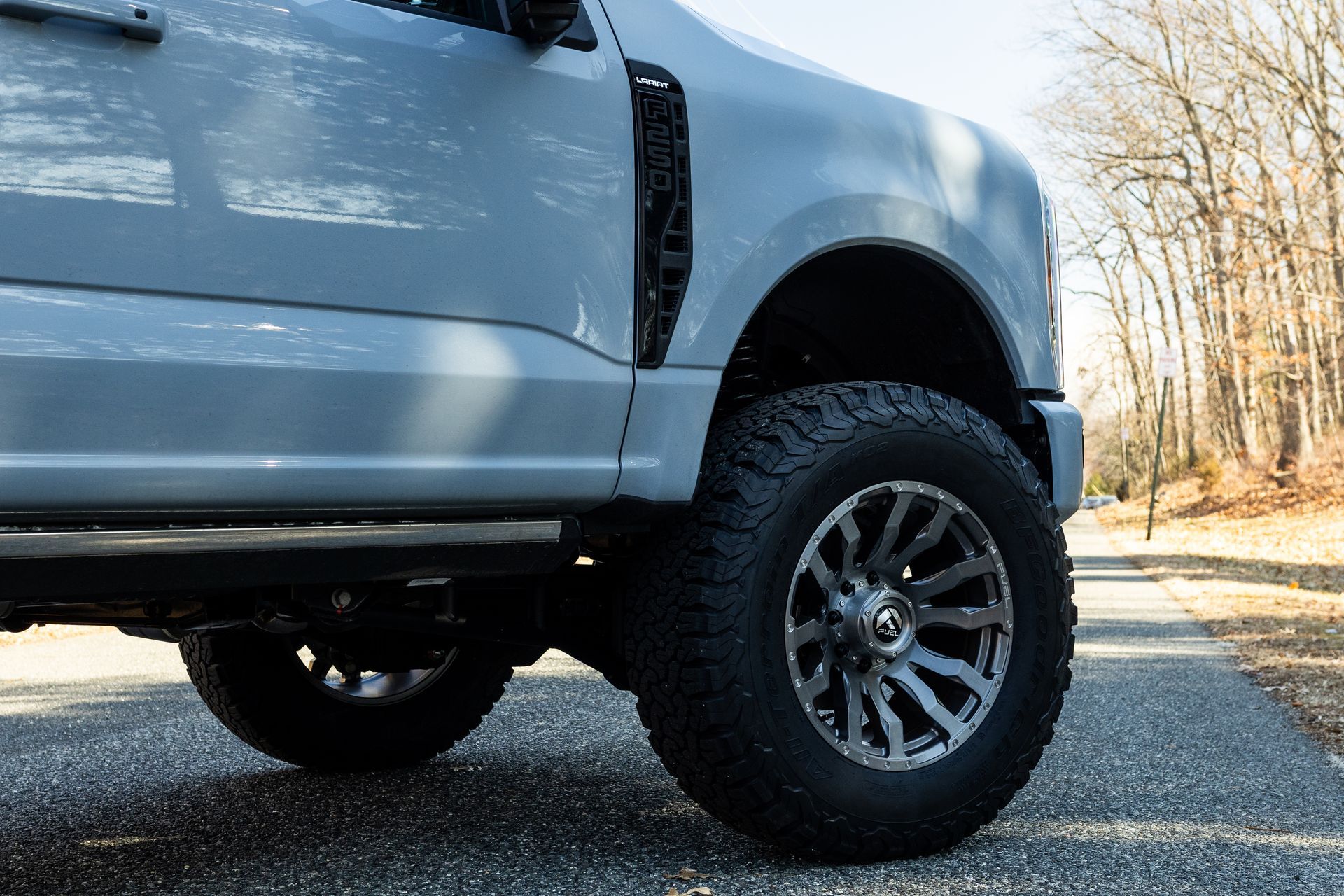 Gray truck with black wheels on a paved road, daytime.