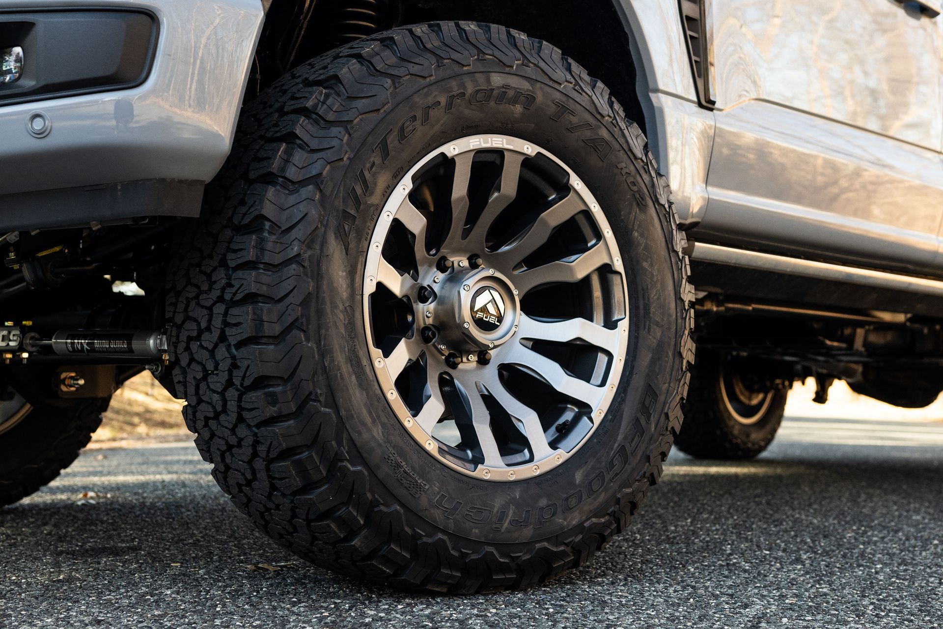 Close-up of a silver truck wheel with a black and silver rim and a large off-road tire.