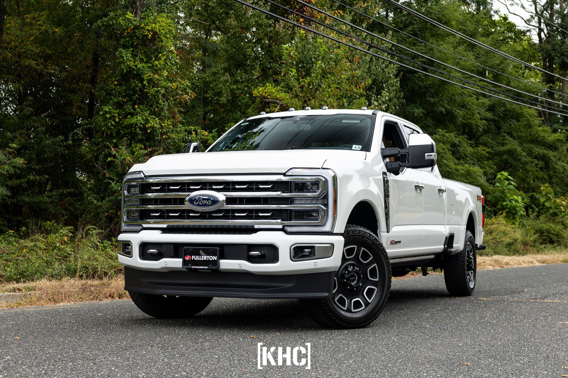 White Ford Super Duty truck parked on asphalt road.