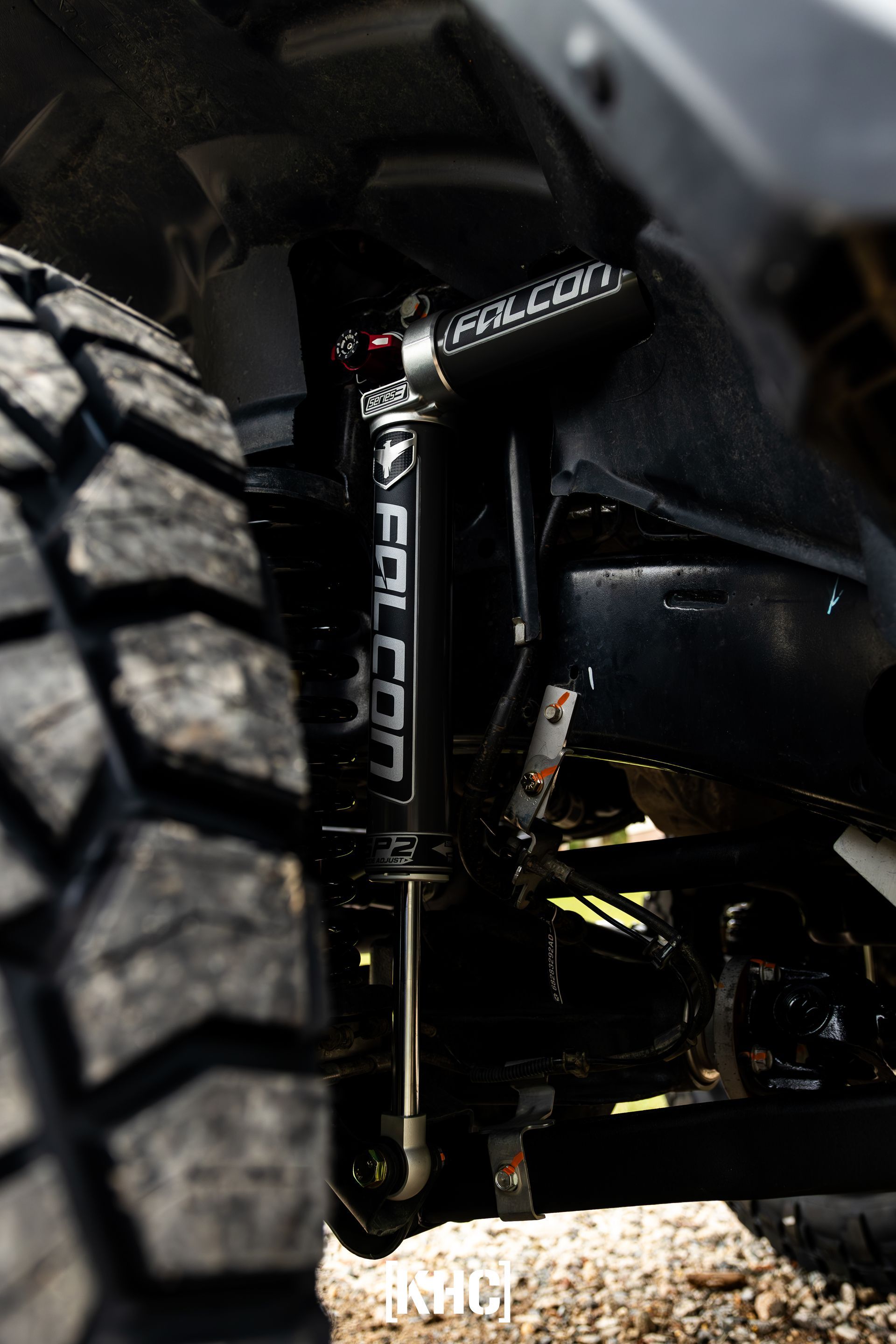 Black Falcon shock absorber on a vehicle, showing lettering, next to a large tire.