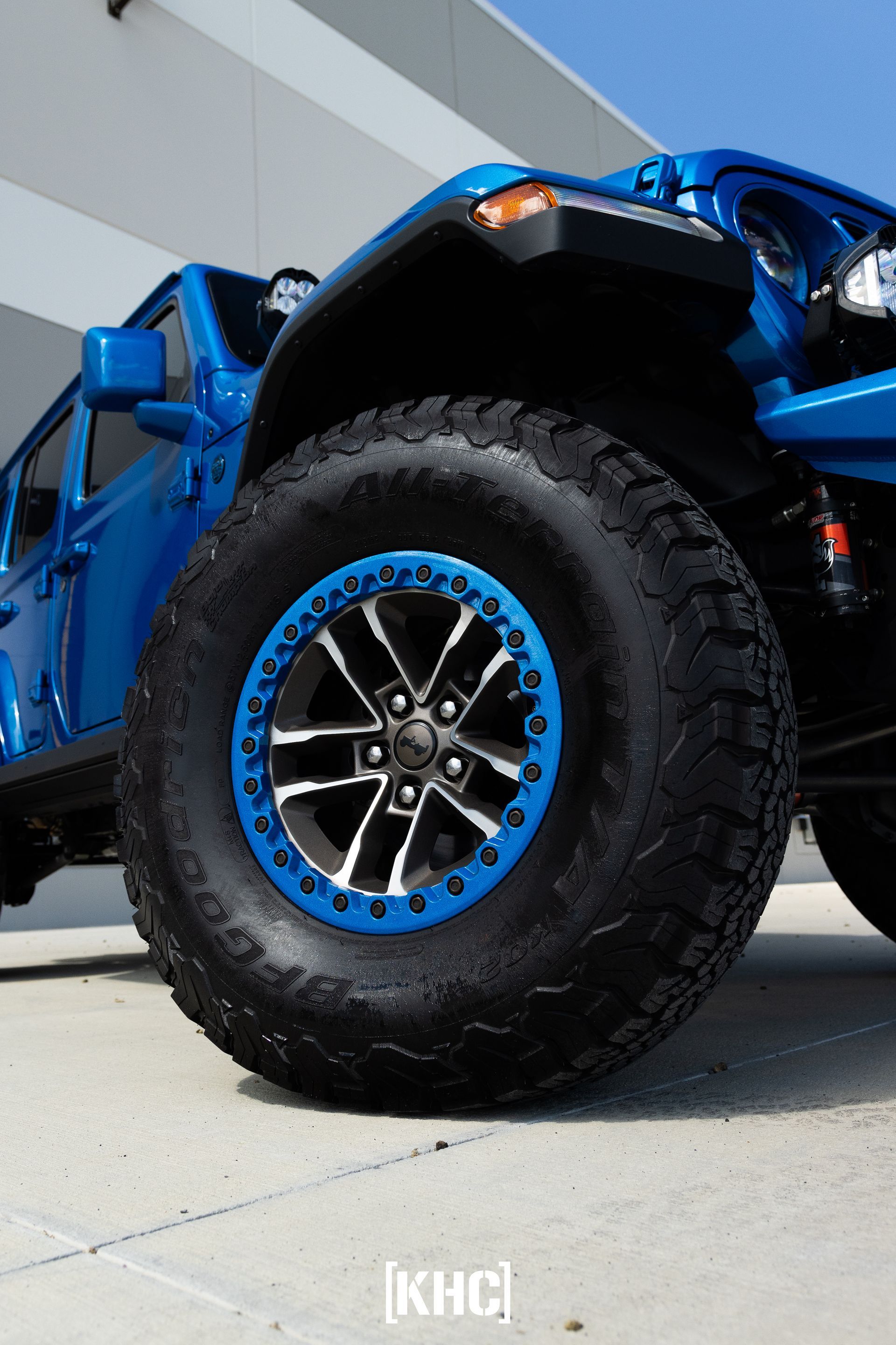 Blue Jeep Wrangler with large off-road tires and blue accents, parked outside.