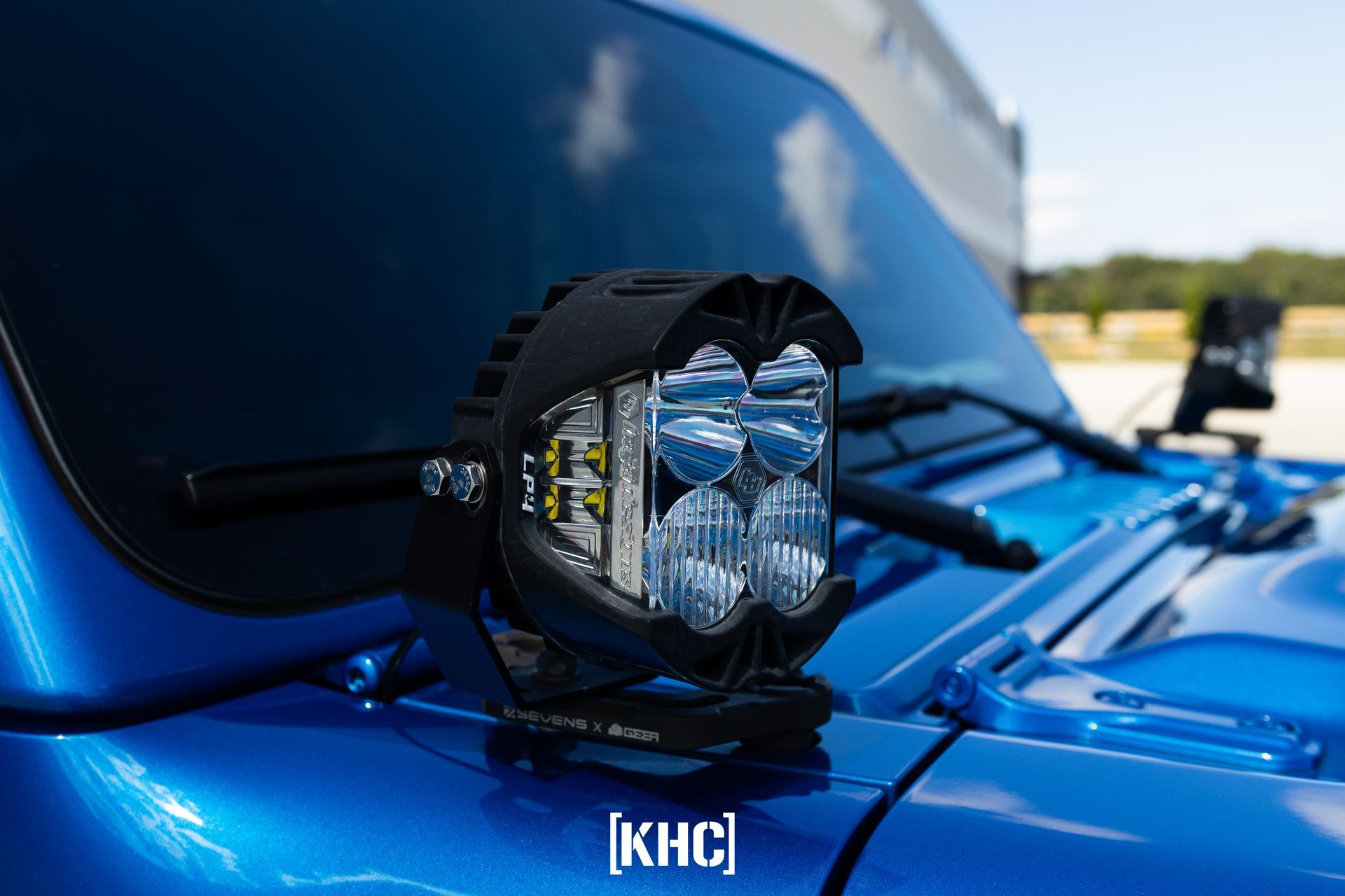 Black LED light mounted on a blue Jeep, near the windshield.