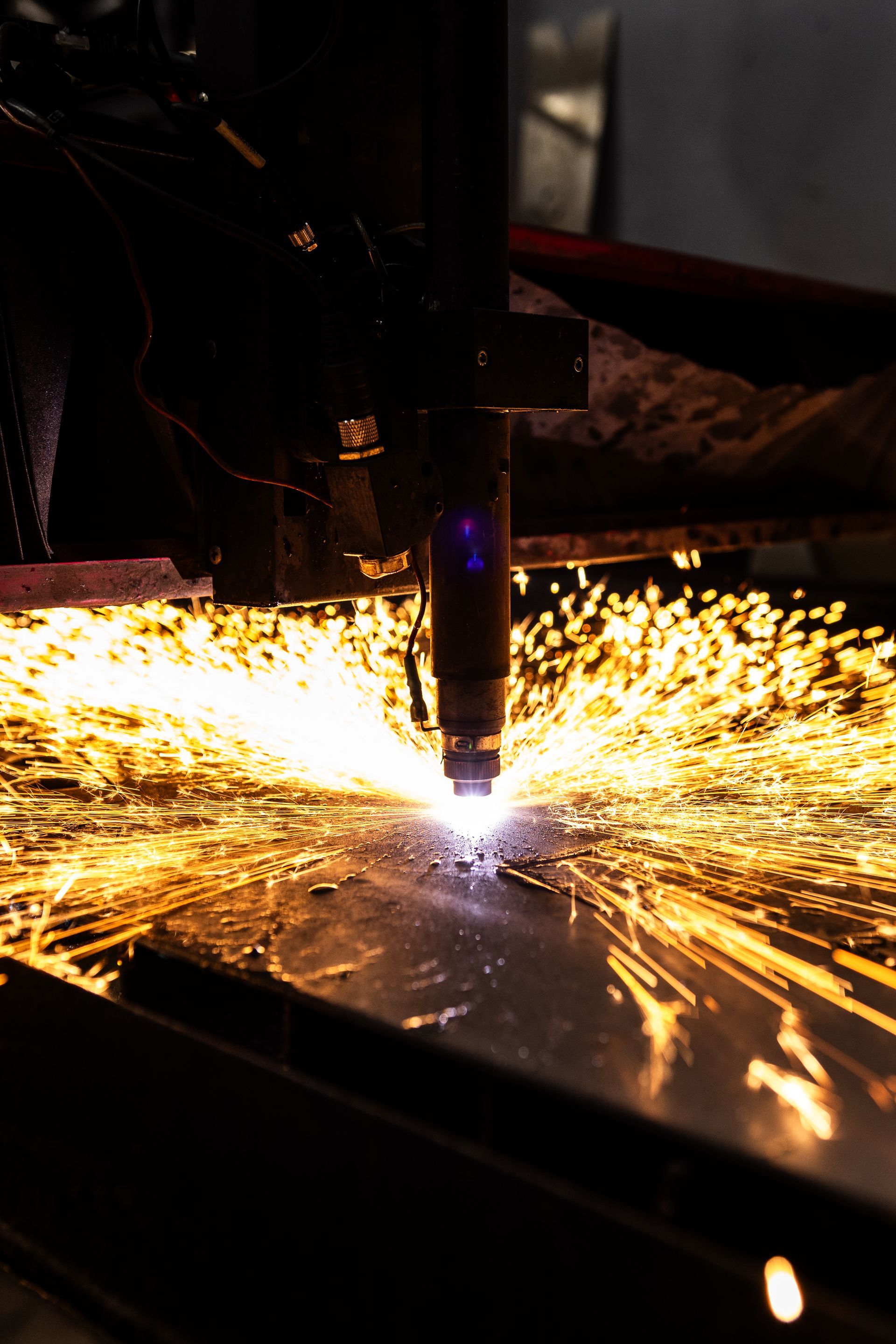 Plasma cutter sparks and melts metal in a dark industrial setting.