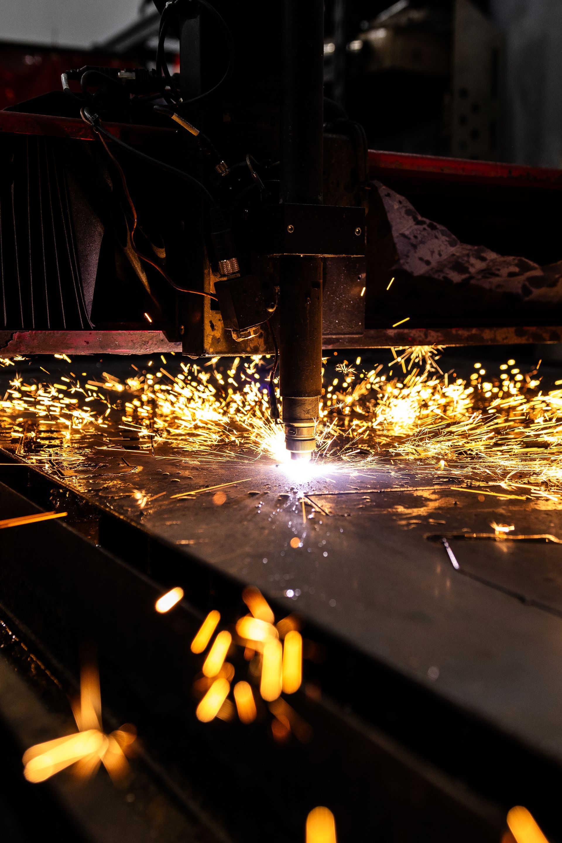 Plasma cutter in action, sparks flying from cutting metal sheet.