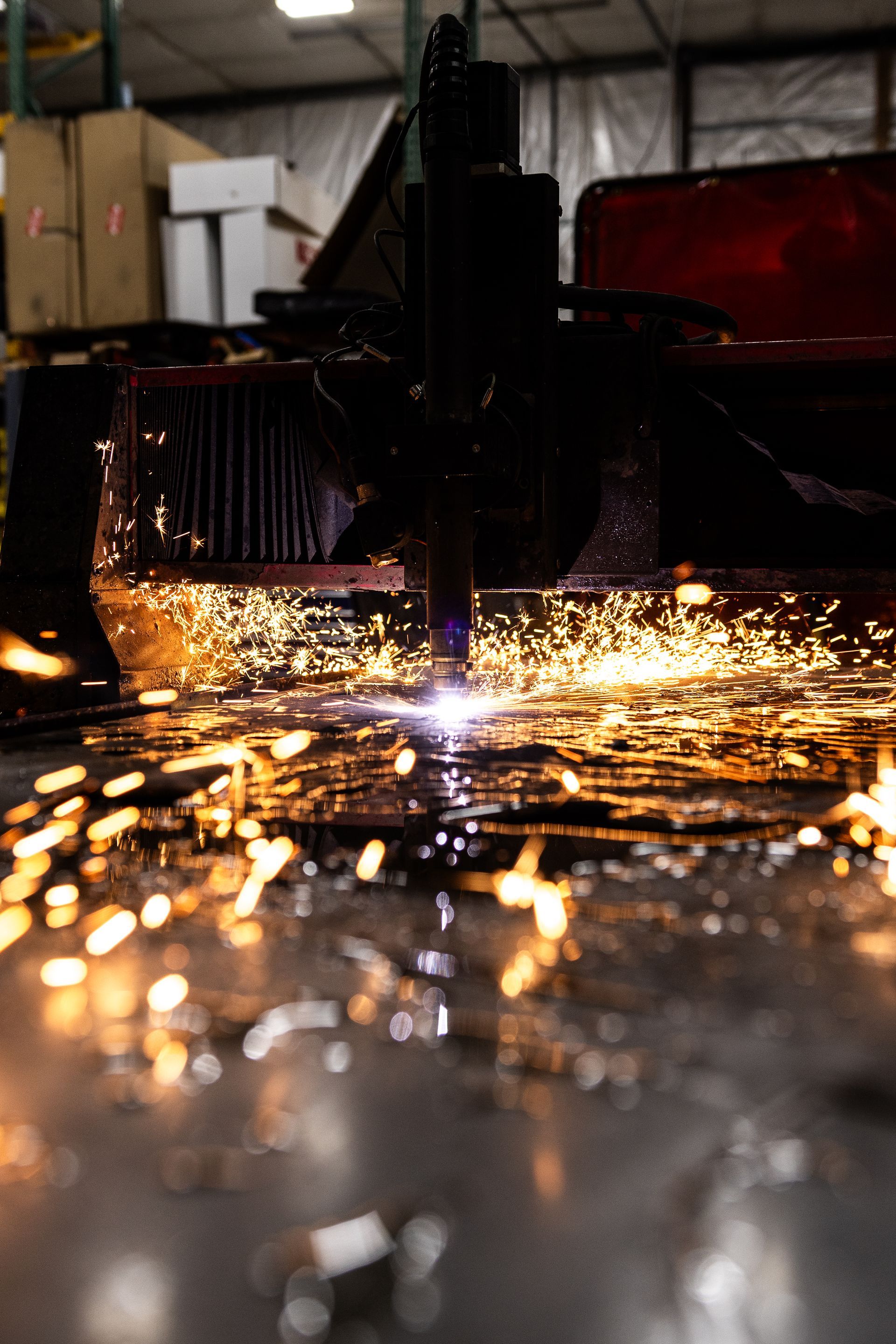 Sparks fly from a metal cutting machine in a workshop.