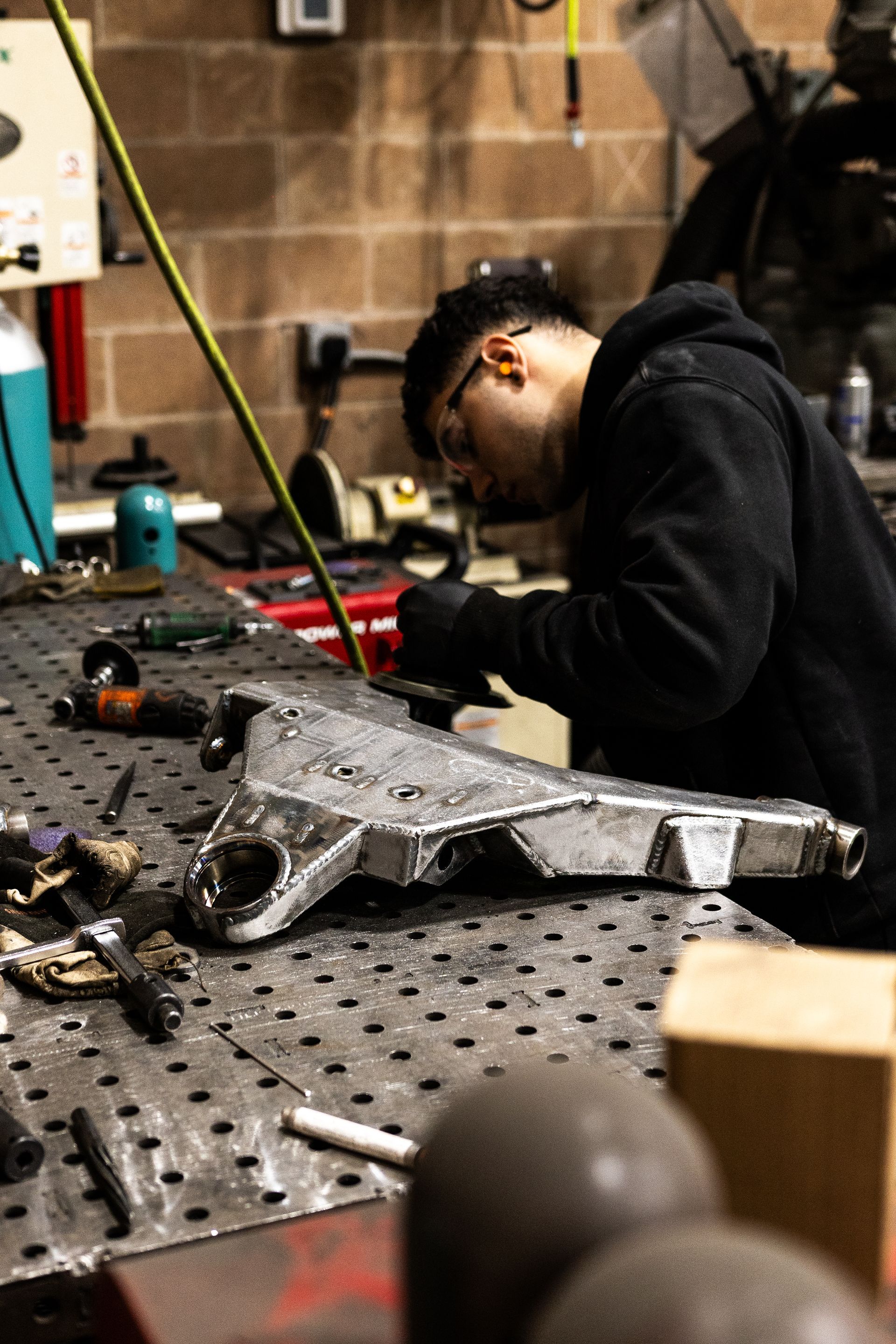 Person welding metal object on a workbench in a workshop.