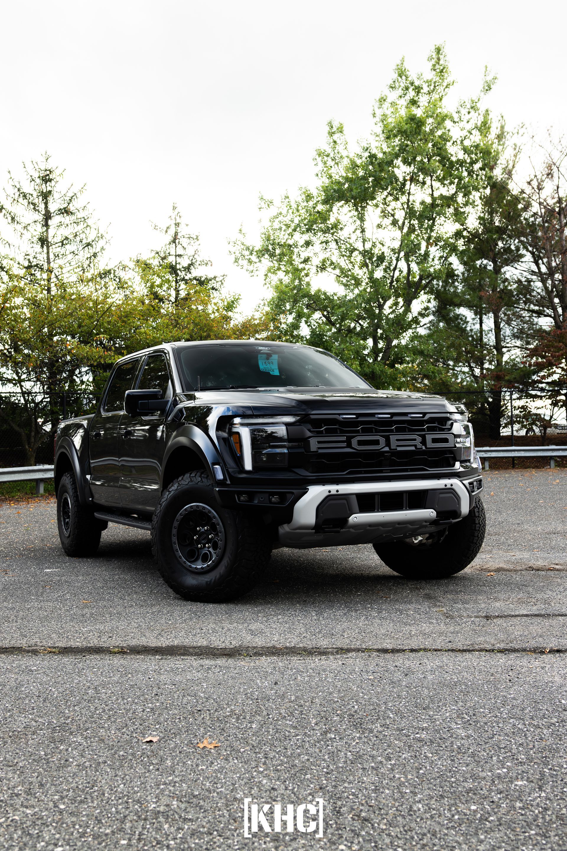 Black Ford Raptor pickup truck parked on asphalt.