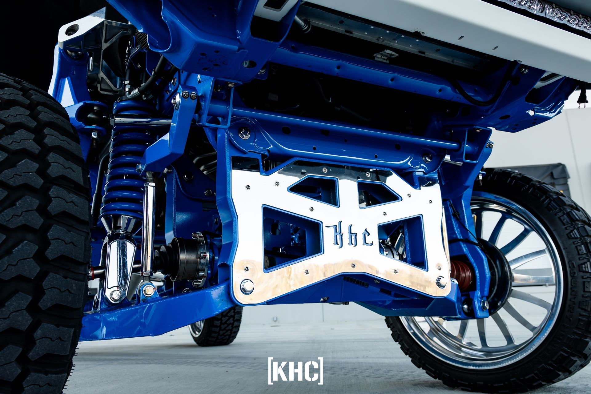 Blue and white truck suspension with custom emblem, showcasing lifted truck modifications.