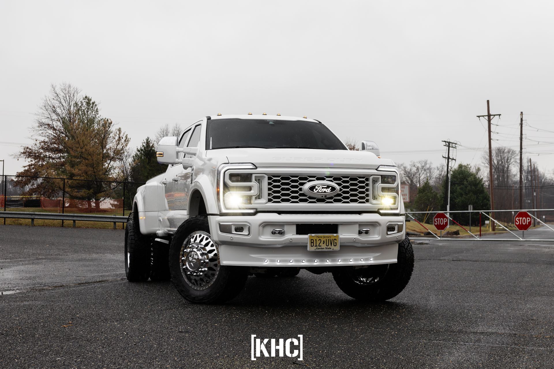 White Ford F-350 dually pickup truck parked on a paved road with trees in the background.