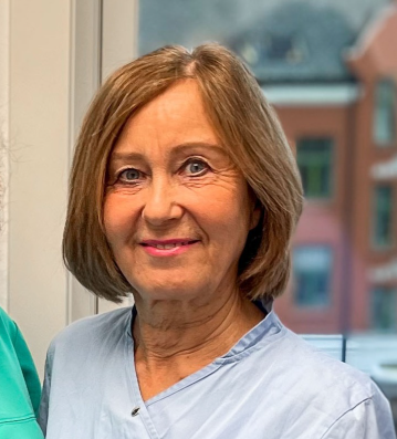 Kvinne som smiler foran et blått fjell- og vannlandskap.