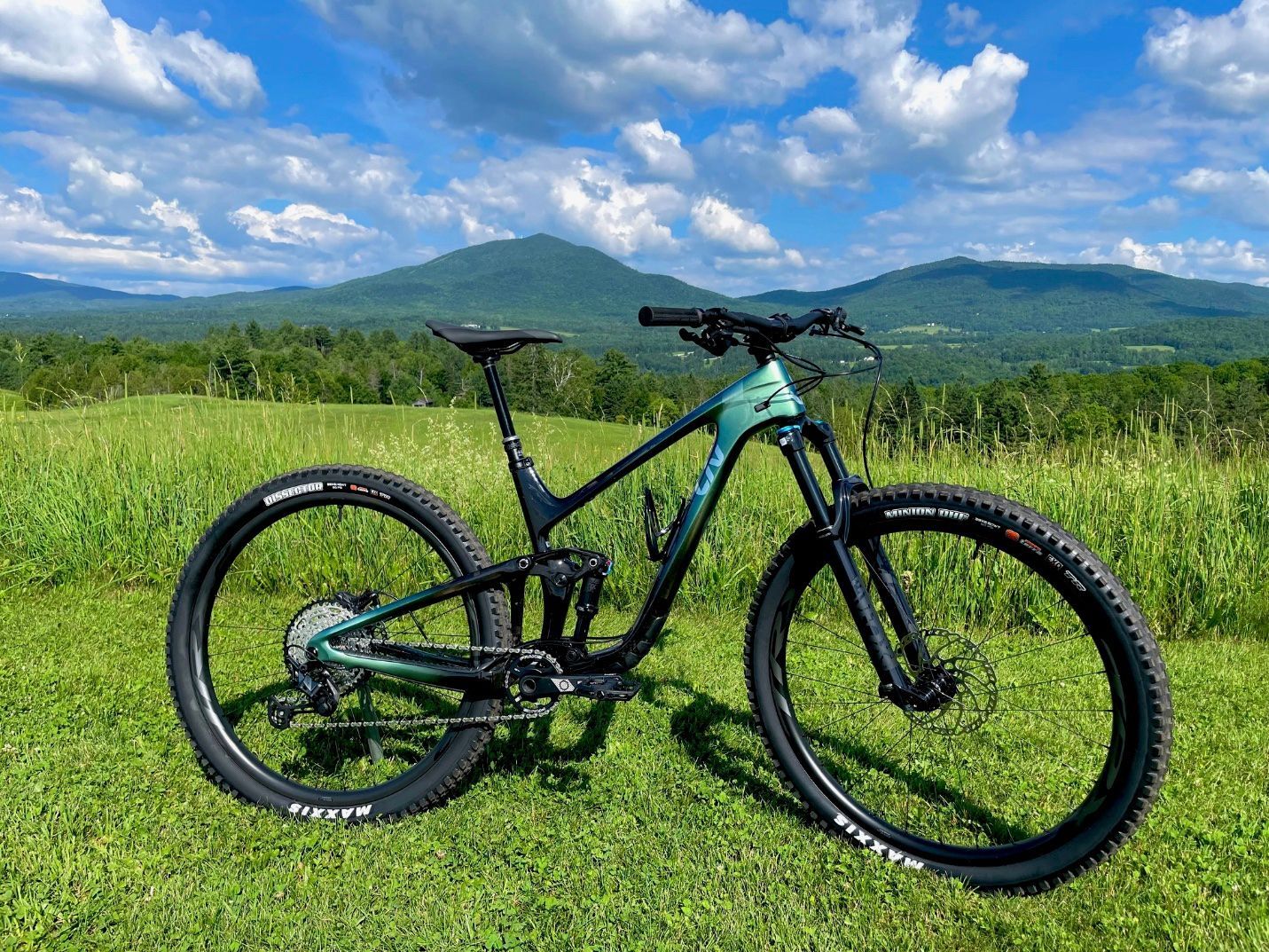Green aluminum Liv Intrigue 2 mountain bike in a field with Burke Mountain, Vermont in the backgroun
