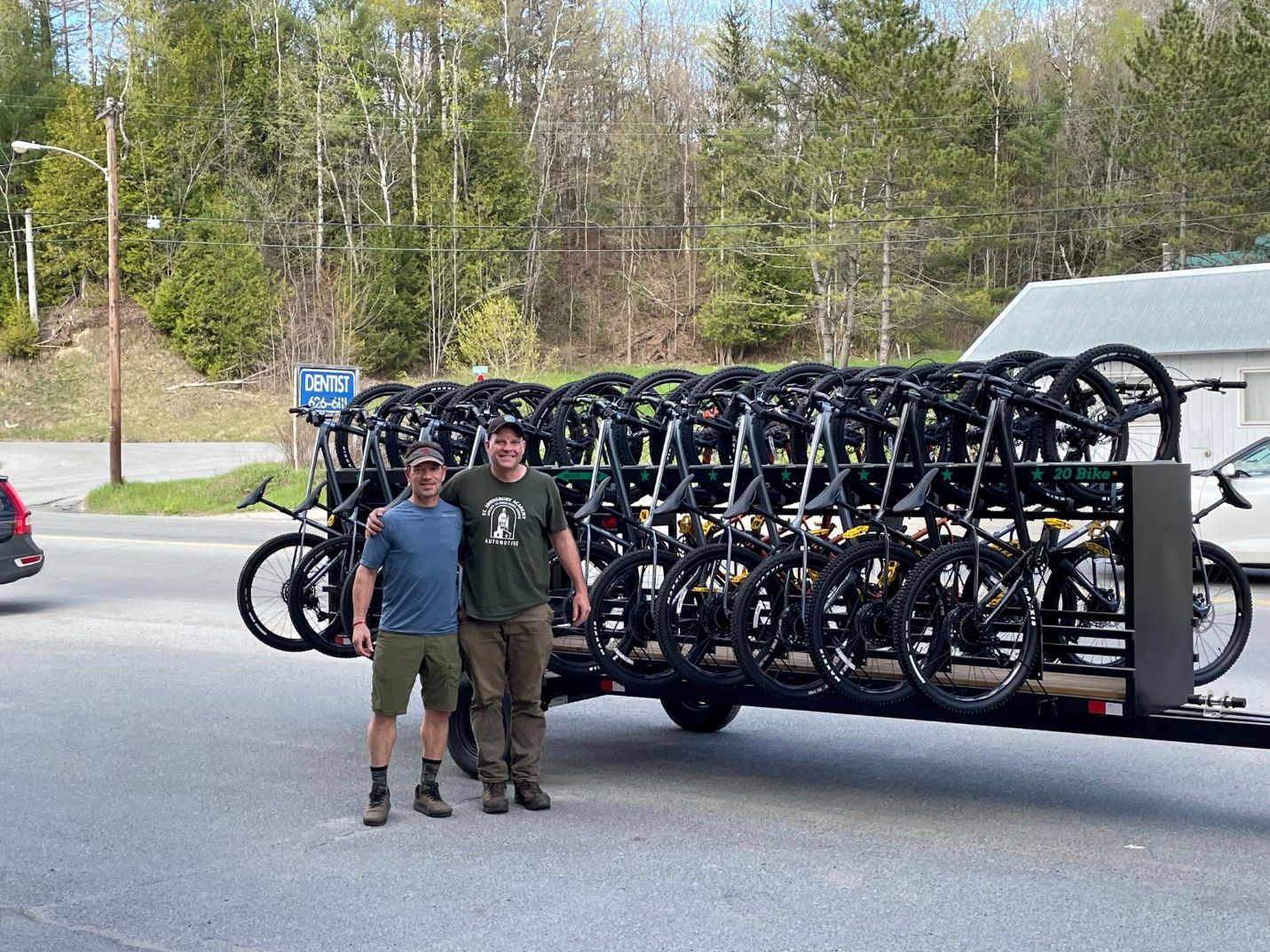 Two people standing in front of a fleet of mountain bikes on a trailor