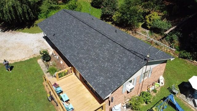 an aerial view of a house with a black roof and a wooden deck Birds Eye Roofing Group.