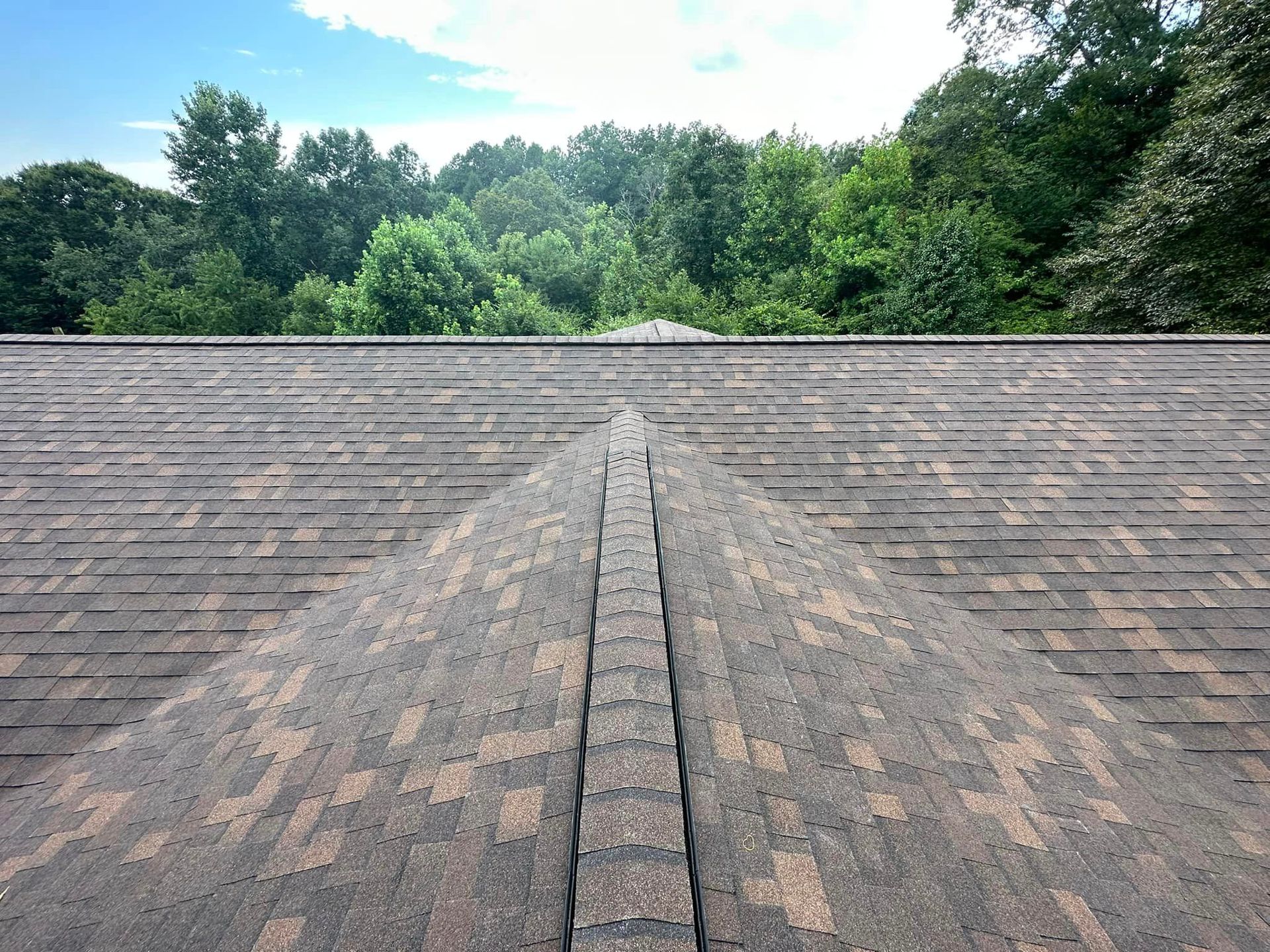 a roof with a lot of shingles and trees in the background Birds Eye Roofing Group services