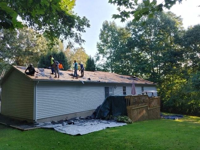 a group of people are working on the roof of a house Birds Eye Roofing Group.