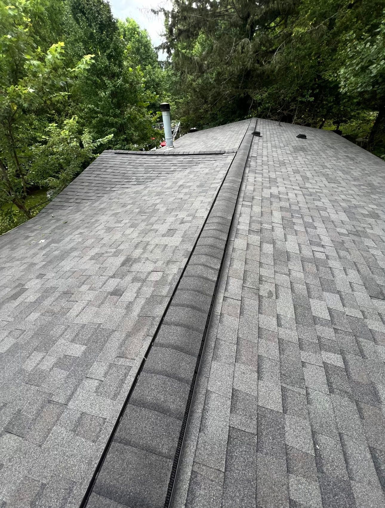 a close up of a roof with trees in the background Birds Eye Roofing Group.