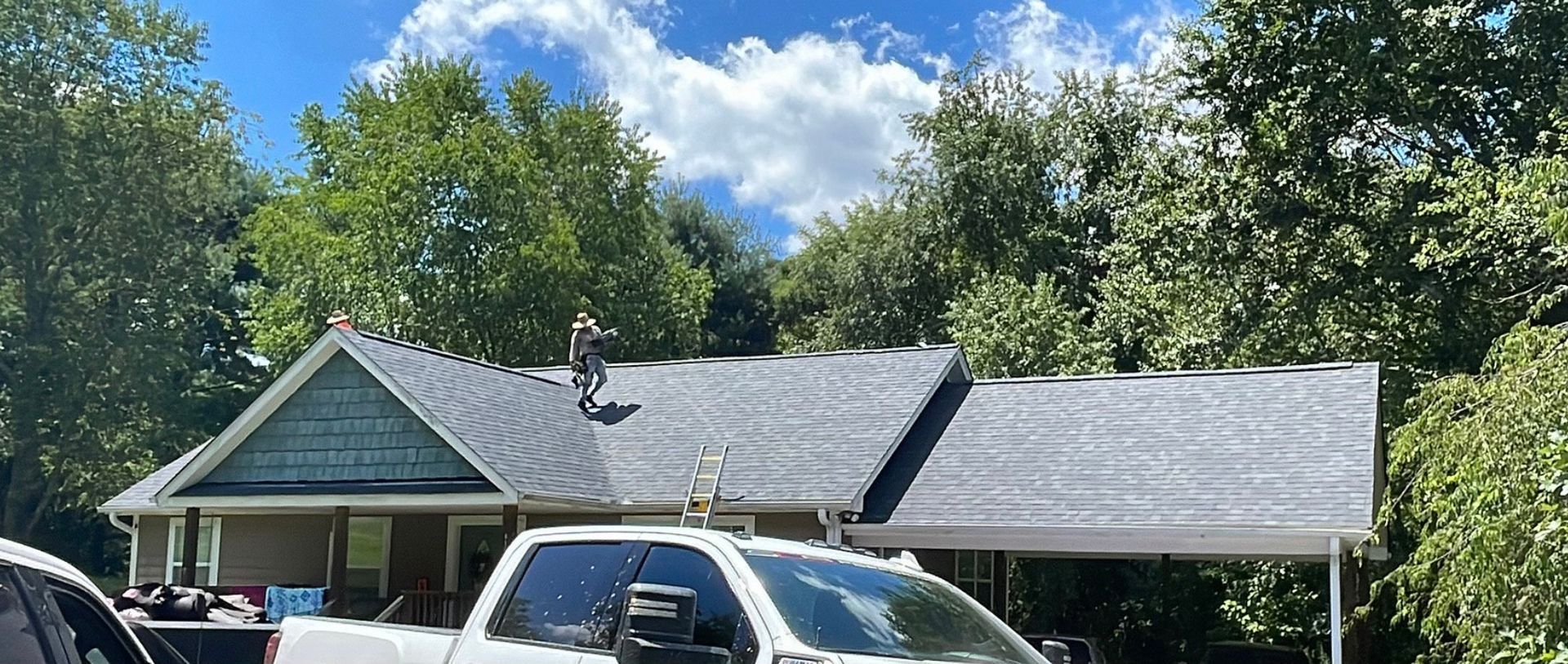 a white truck is parked in front of a house Birds Eye Roofing Group.