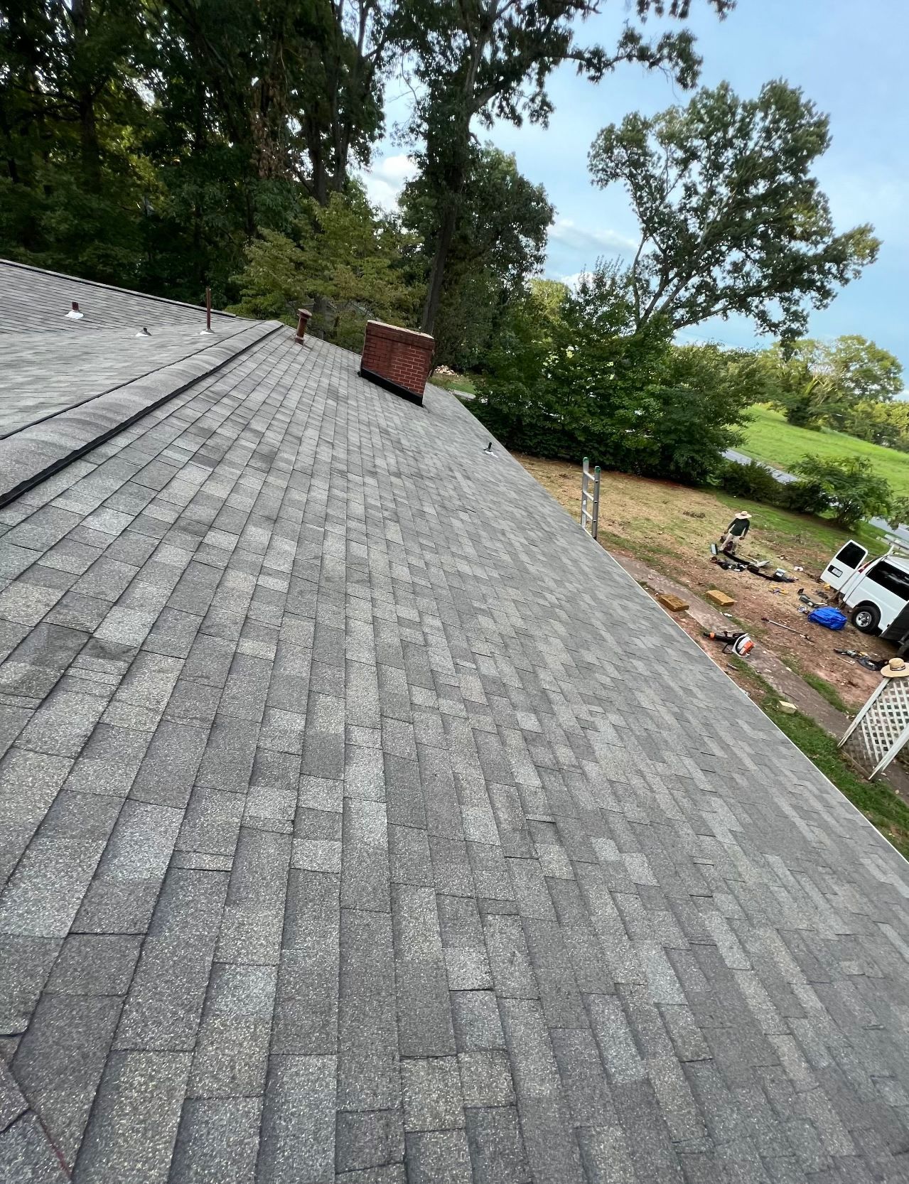a roof with a chimney on it and trees in the background Birds Eye Roofing Group.