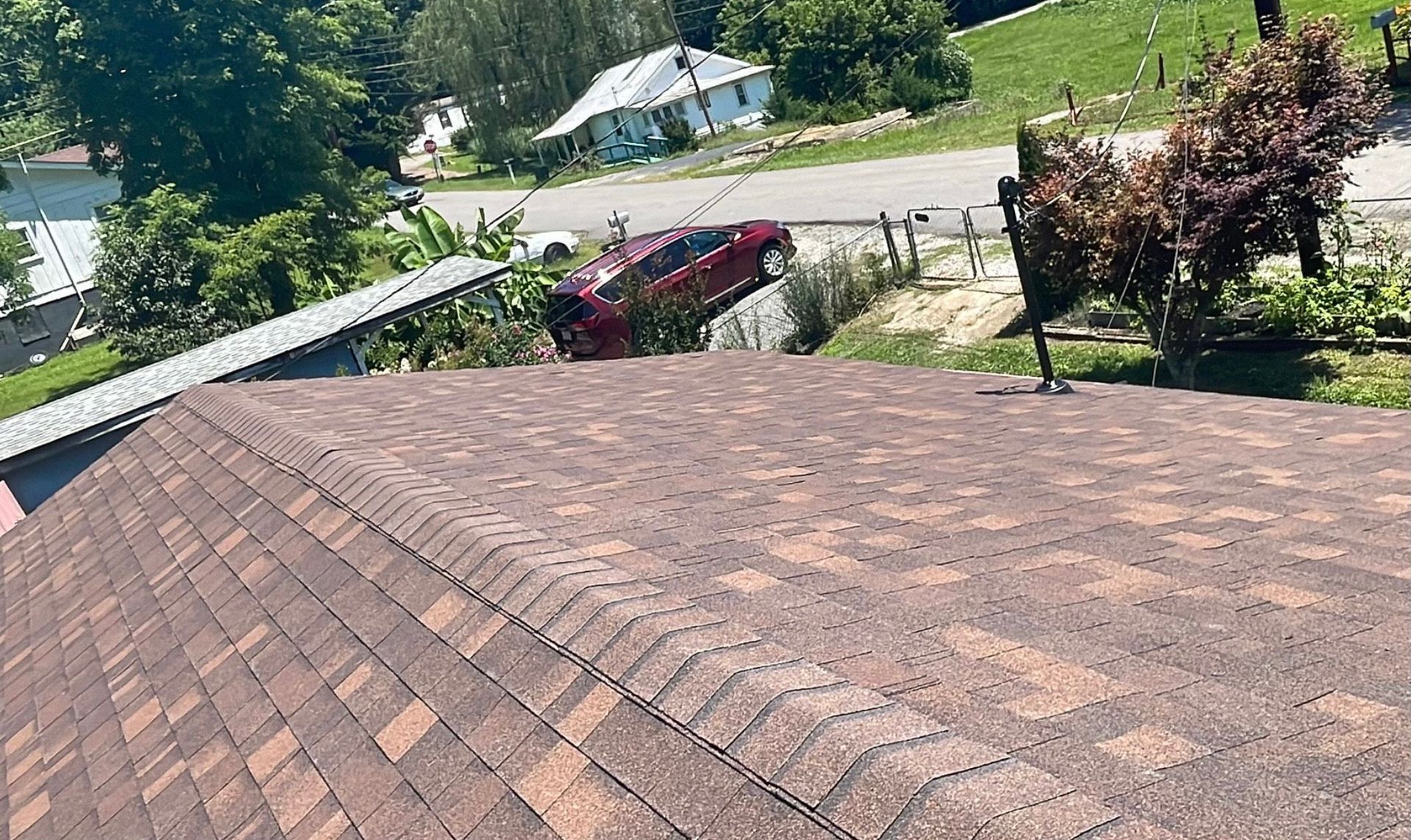 a red car is sitting on the roof of a house Birds Eye Roofing Group.