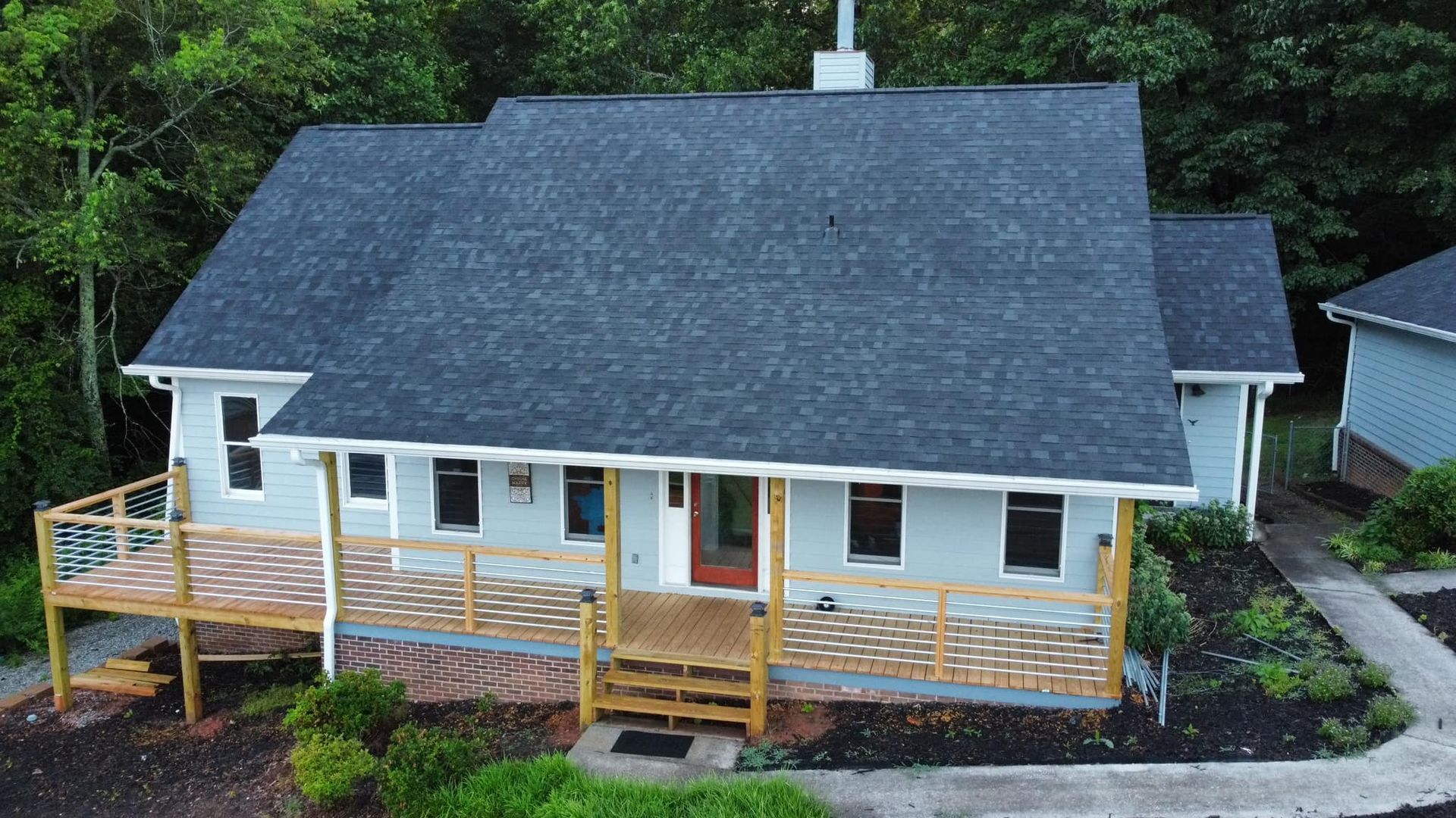 an aerial view of a house with a large porch surrounded by trees Birds Eye Roofing Group.
