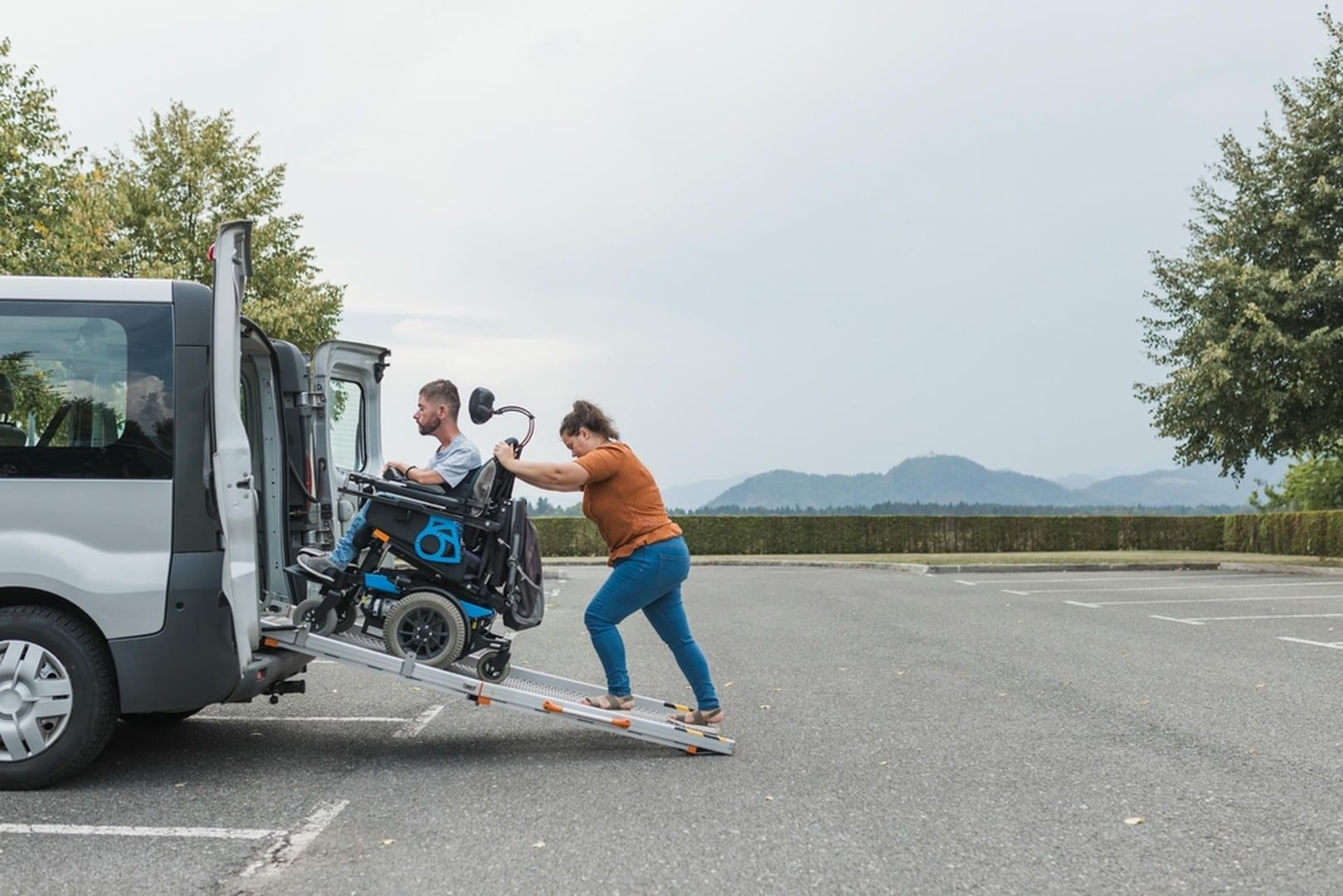 A woman is pushing a wheelchair into the back of a van.