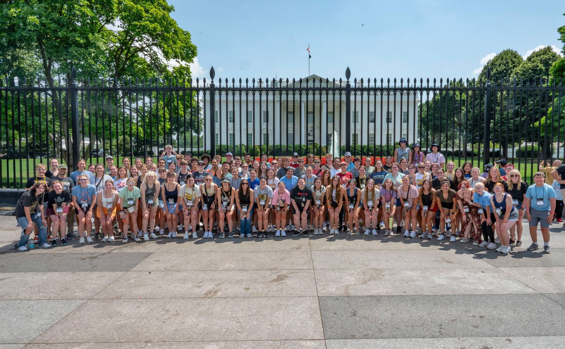 A large group of people are posing for a picture in front of the white house
