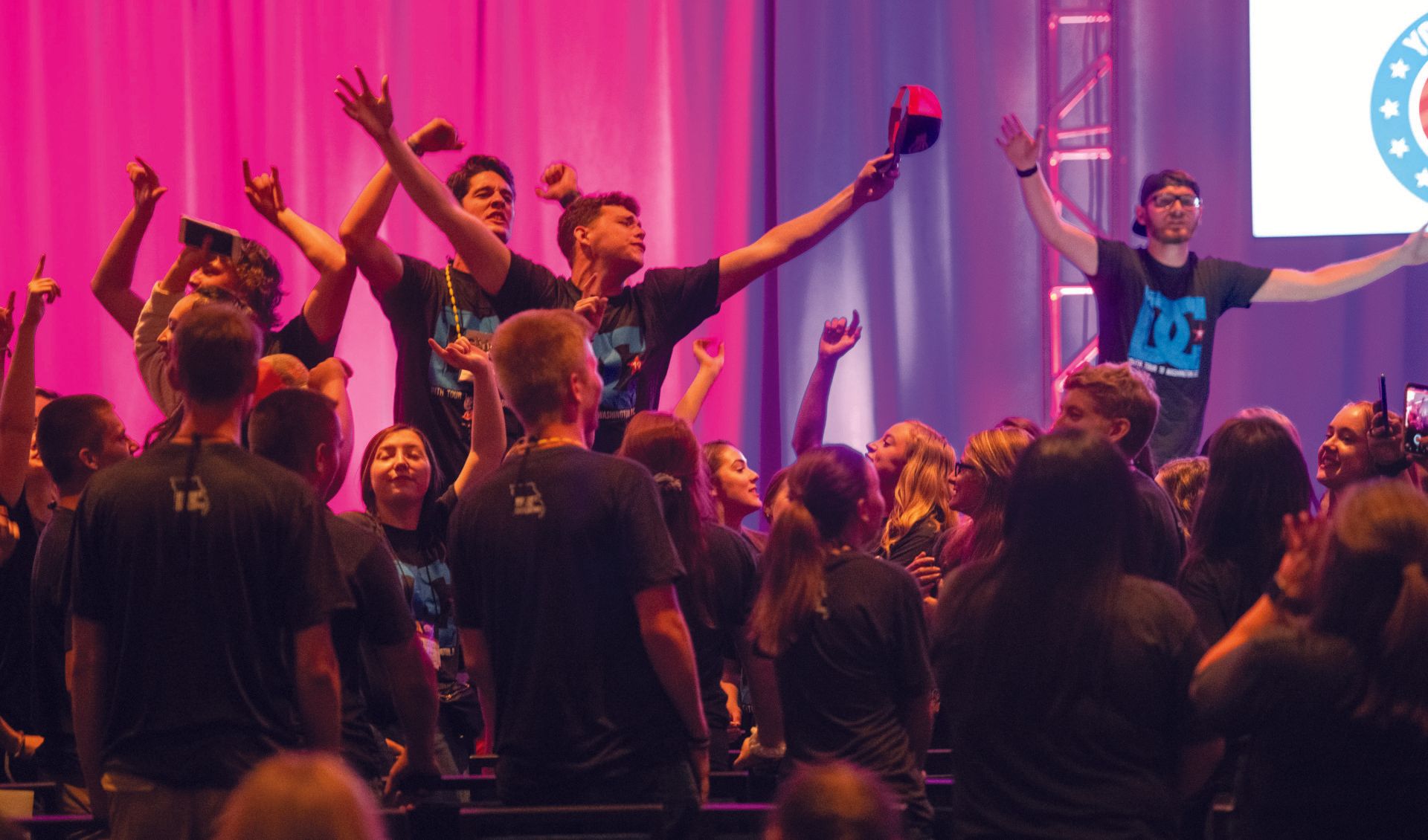 A group of people are standing on a stage with their arms in the air.