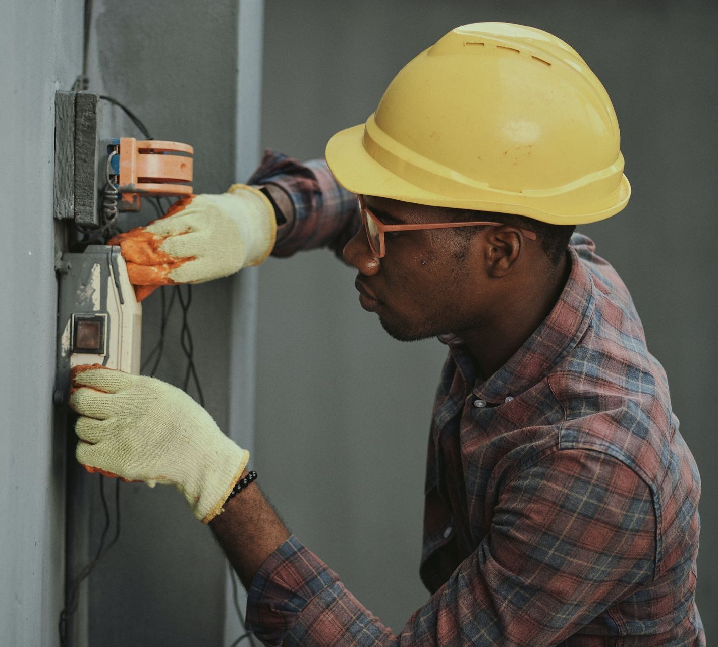 A person is fixing an electrical outlet with a screwdriver.