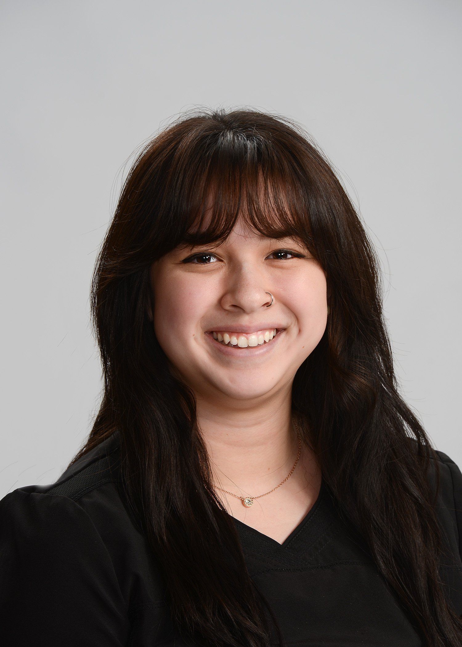 A woman with long hair and bangs is smiling for the camera.