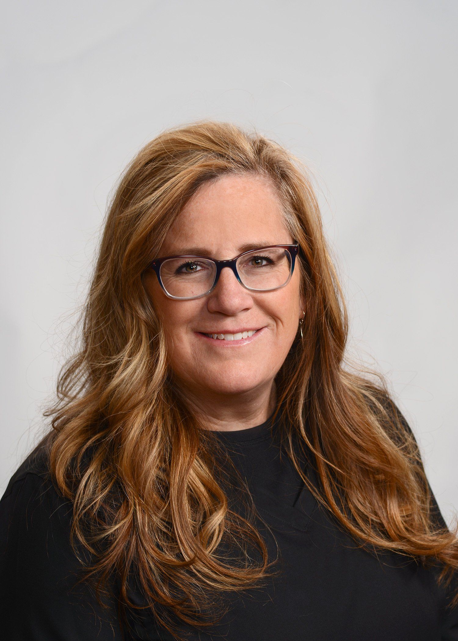 A woman wearing glasses and a black shirt is smiling for the camera.