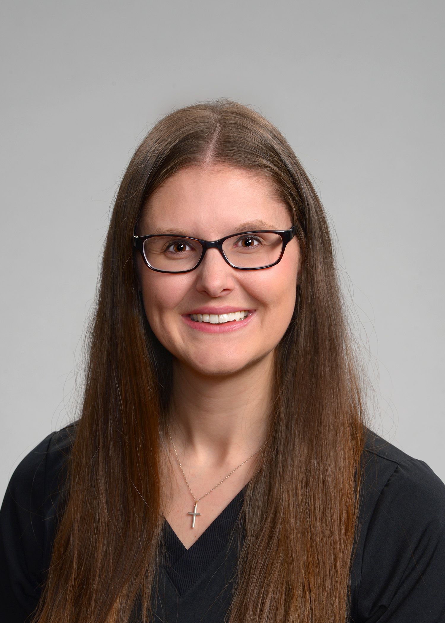 A woman wearing glasses and a black shirt is smiling for the camera.